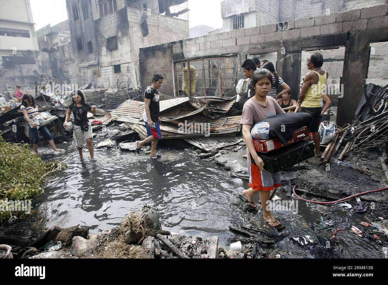 Les résidents portent leurs effets personnels récupérés dans leurs maisons incendiées après un incendie dans un bidonville à Manille, aux Philippines, le 23 mars 2014. Le Bureau philippin de la protection contre les incendies a estimé qu'environ 200 à 300 maisons avaient été rasées par l'incendie, affectant plus de 1 000 familles dans la région. (Xinhua/Rouelle Umali) PHILIPPINES-MANILA-FIRE PUBLICATIONxNOTxINxCHN les résidents portent leurs membres du personnel récupérés dans leurs maisons brûlées après un incendie DANS un bidonville à Manille Philippines Mars 23 2014 le Bureau philippin de la protection contre les incendies a estimé que Thatcher environ 200 à 300 maisons étaient Banque D'Images