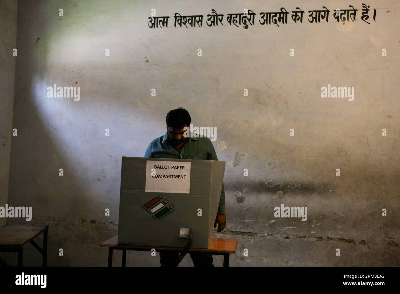 (140410) -- HARYANA, 10 avril 2014 (Xinhua) -- Un électeur vote dans un bureau de vote avec des mots en hindi signifiant être un homme confiant et courageux écrit sur le mur du village de Jhadsa, dans l'État de Haryana, en Inde, le 10 avril 2014. Le vote est en cours jeudi dans une atmosphère généralement pacifique dans 91 circonscriptions à travers 11 États de l'Inde, y compris la capitale New Delhi, dans la troisième phase des élections législatives considérées comme critiques à la fois pour le parti au pouvoir du Congrès et pour le parti d'opposition Bharatiya Janata Party (BJP). (Xinhua/Zheng Huansong) INDE-HARYANA-ELECTIONS GÉNÉRALES-VOTE PUBLICATIONxNOTxINxCHN Banque D'Images