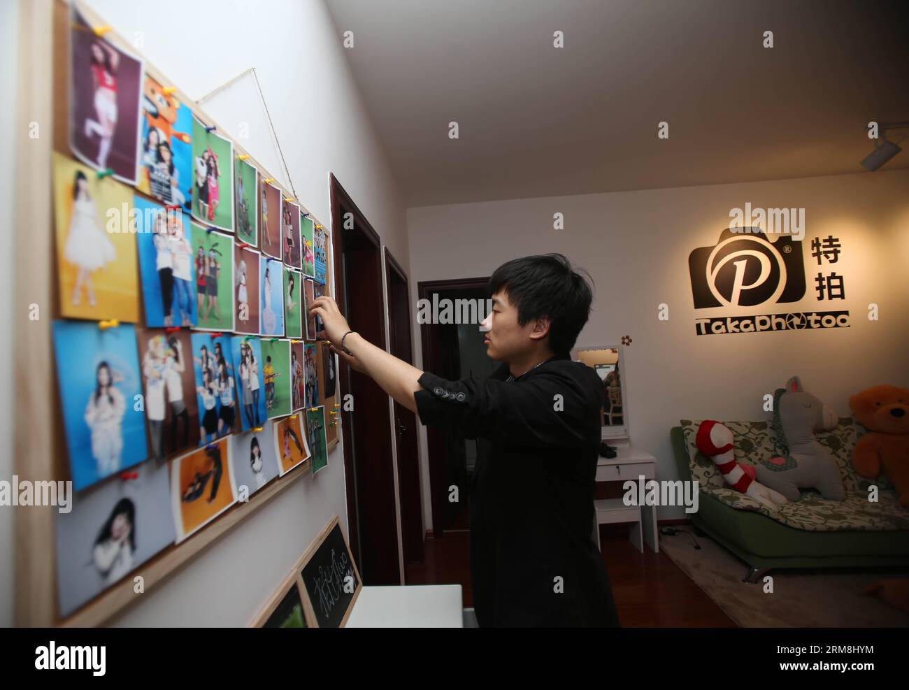 CHANGSHA, 15 avril 2014 (Xinhua) -- Zeng Jun pose des autoportraits de clients sur un mur pour une démonstration dans son studio photo Takaphotoo à Changsha, capitale de la province du Hunan en Chine centrale, le 15 avril 2014. En mars, Zeng Jun et son camarade de classe Yuan Chunzi ont ouvert Takaphotoo, un studio photo en libre-service dans lequel les clients sont autorisés à prendre des photos pour eux-mêmes. Dans une cabine photo où l'appareil photo et l'éclairage sont déjà réglés, ce que les clients doivent faire est de poser devant l'objectif et d'appuyer sur l'obturateur à distance. Les deux jeunes entrepreneurs croient que cela fera de leurs clients fe Banque D'Images