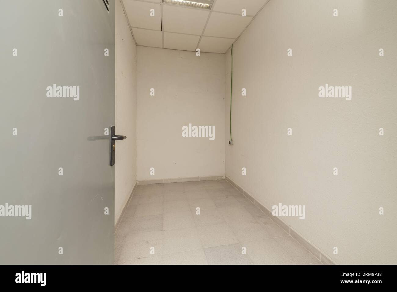 Une petite salle de stockage vide avec des plafonds techniques et des sols en céramique grise Banque D'Images