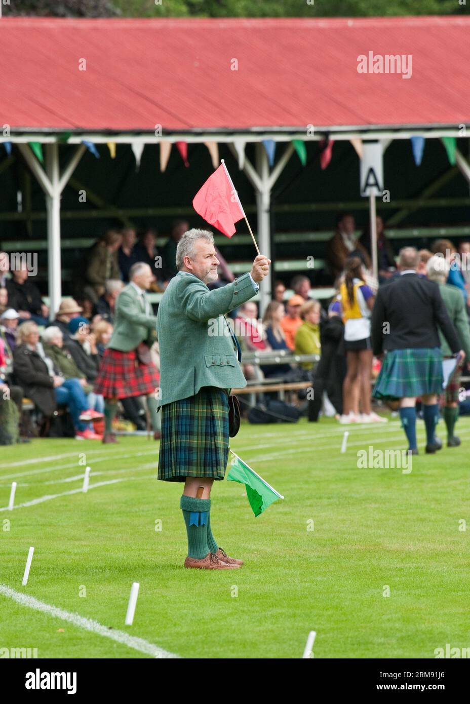 Juge de la concurrence avec drapeau rouge. The Braemar Gathering, Highland Games. Aberdeenshire. Banque D'Images