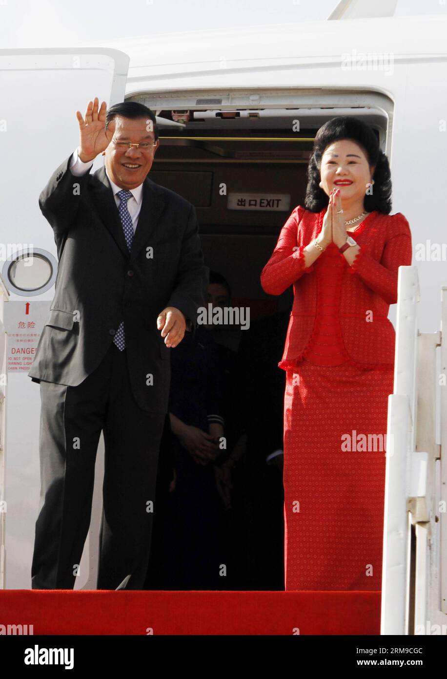 Le Premier ministre cambodgien Hun Sen (à gauche) et son épouse Bun Rany font un geste à l’aéroport international de Phnom Penh à Phnom Penh le 18 mai 2014. Hun Sen s’est rendu dimanche matin à Shanghai, dans l’est de la Chine, pour assister au 4e Sommet de la Conférence sur l’interaction et les mesures de confiance en Asie (CICA), qui se tiendra mardi et mercredi. (Xinhua/Sovannara) CAMBODGE-PM-CHINE-SHANGHAI-CICA PUBLICATIONxNOTxINxCHN Banque D'Images