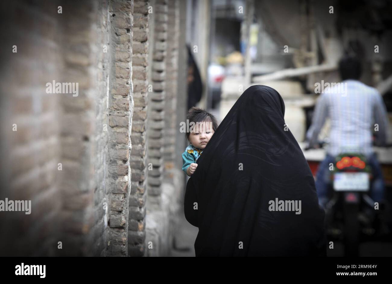 (140520) -- TÉHÉRAN, 20 mai 2014 (Xinhua) -- Une femme vêtue de tchador porte son enfant dans une ruelle à Téhéran, capitale de l'Iran, le 19 mai 2014. Chador est une sorte de hijab formel pour de nombreuses femmes en Iran dans les lieux publics. Le hijab, une couverture des cheveux et du corps pour les femmes, a été rendu public après la révolution islamique en Iran en 1979. (Xinhua/Ahmad Halabisaz)(zhf) IRAN-TEHRAN-WOMEN-HIJAB PUBLICATIONxNOTxINxCHN TÉHÉRAN Mai 20 2014 XINHUA une femme vêtue de chador porte son enfant SUR une allée à TÉHÉRAN capitale de l'Iran Mai 19 2014 chador EST un enfant du hijab formel pour BEAUCOUP DE femmes en Iran en public PL Banque D'Images
