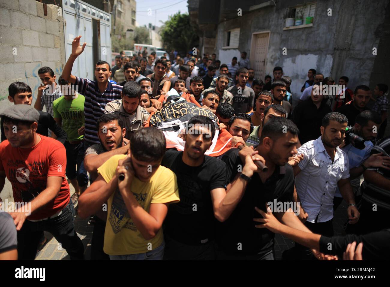 (140712) -- Gaza, 12 juillet 2014 (Xinhua) - des personnes en deuil portent le corps du militant palestinien du Jihad islamique Mohammed Sweilem, tué lors d'une frappe aérienne israélienne dans le camp de réfugiés de Jabalya, dans le Nord de la bande de Gaza, le 12 juillet 2014. Israël a pilonné des militants palestiniens dans la bande de Gaza samedi pour un cinquième jour, tuant neuf personnes, dont deux femmes handicapées, ont déclaré des médecins. Le ministère palestinien de la Santé a déclaré dans un communiqué de presse que depuis le début de l’offensive israélienne sur la bande de Gaza tôt mardi, 121 Palestiniens ont été tués et plus de 900 blessés. (Xinhua/Wissam Nassar) M. Banque D'Images