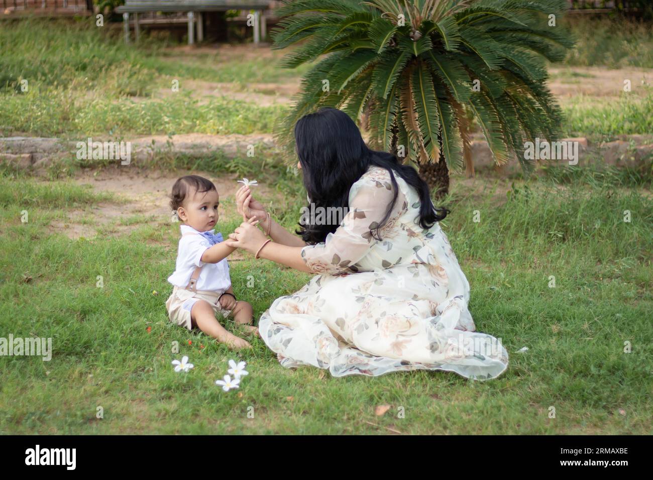 mère donnant fleur à bébé garçon mignon et profitant l'un de l'autre à l'extérieur Banque D'Images