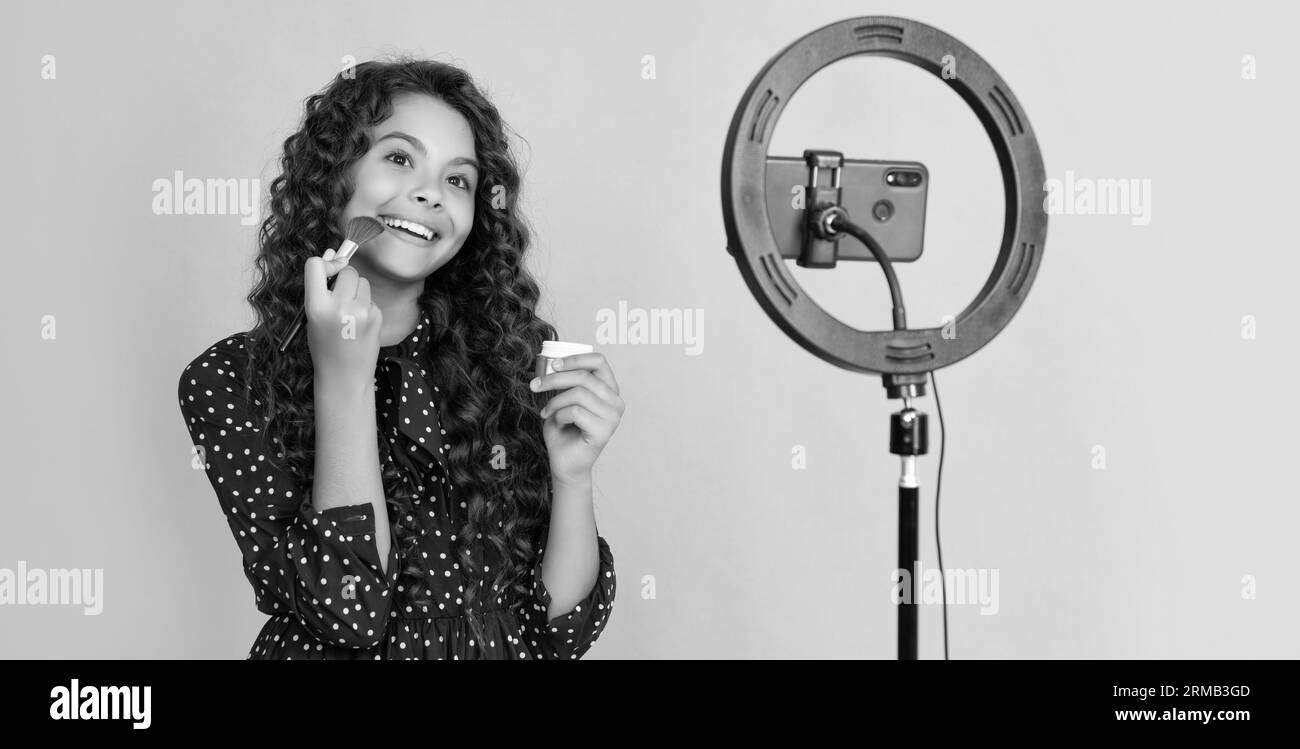 fille gaie avec les cheveux longs bouclés faire la vidéo pour blog tenir la brosse de poudre Banque D'Images