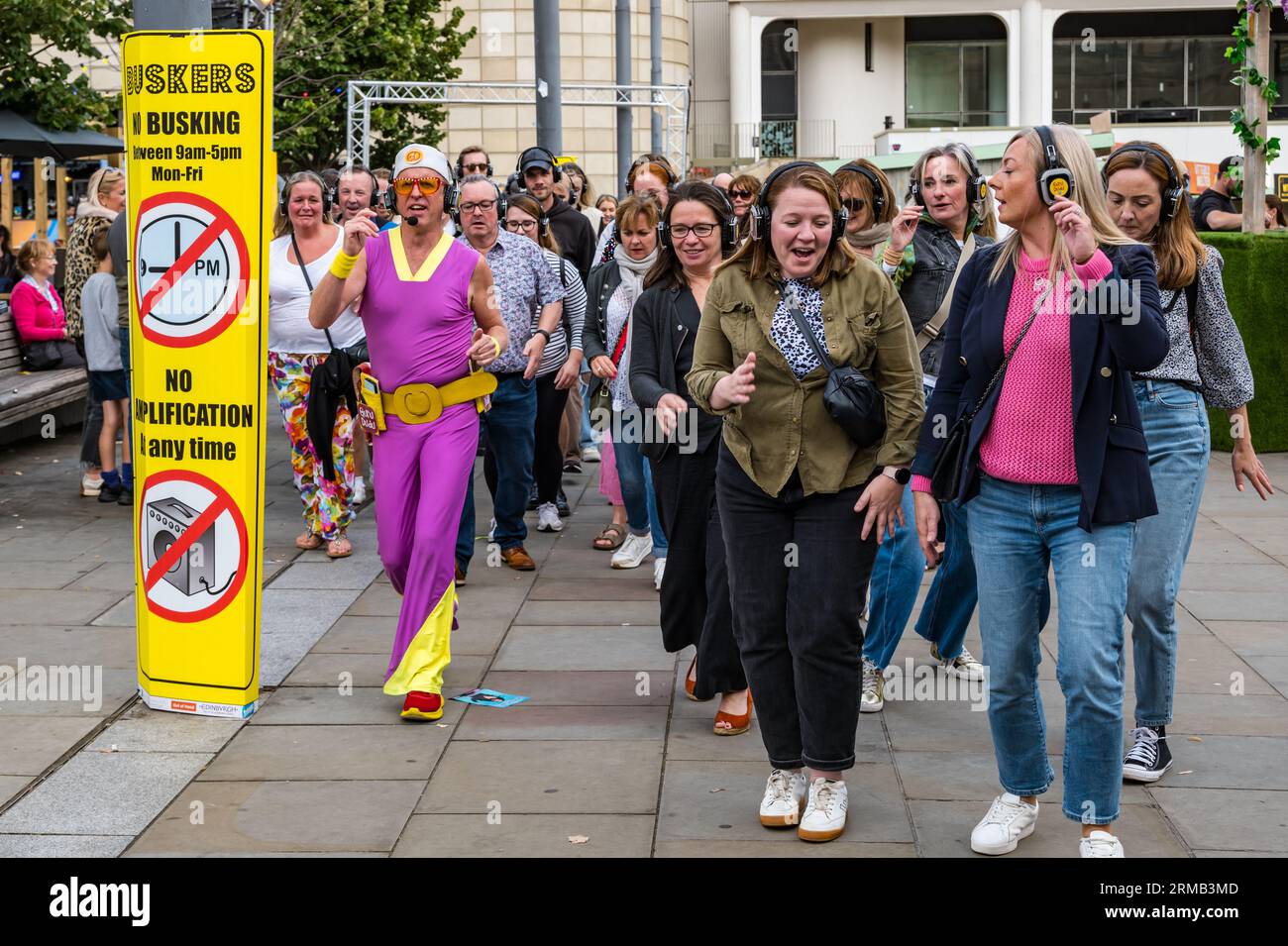 Édimbourg, Écosse, Royaume-Uni, 27 août 2023. Silent Disco : un grand groupe aime la musique à travers des écouteurs alors qu'ils sont conduits autour de la ville dansant sur la musique pop seulement ils peuvent entendre. Crédit : Sally Anderson/Alamy Live News Banque D'Images