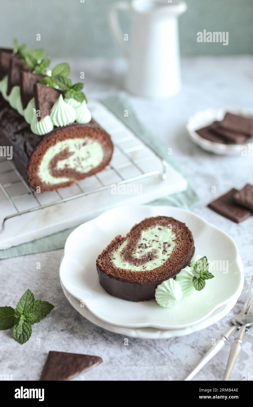 Rouleau de gâteau à la menthe au chocolat. Délicieux dessert maison. Feuilles de menthe fraîche, serviette verte et assiette blanche. Banque D'Images