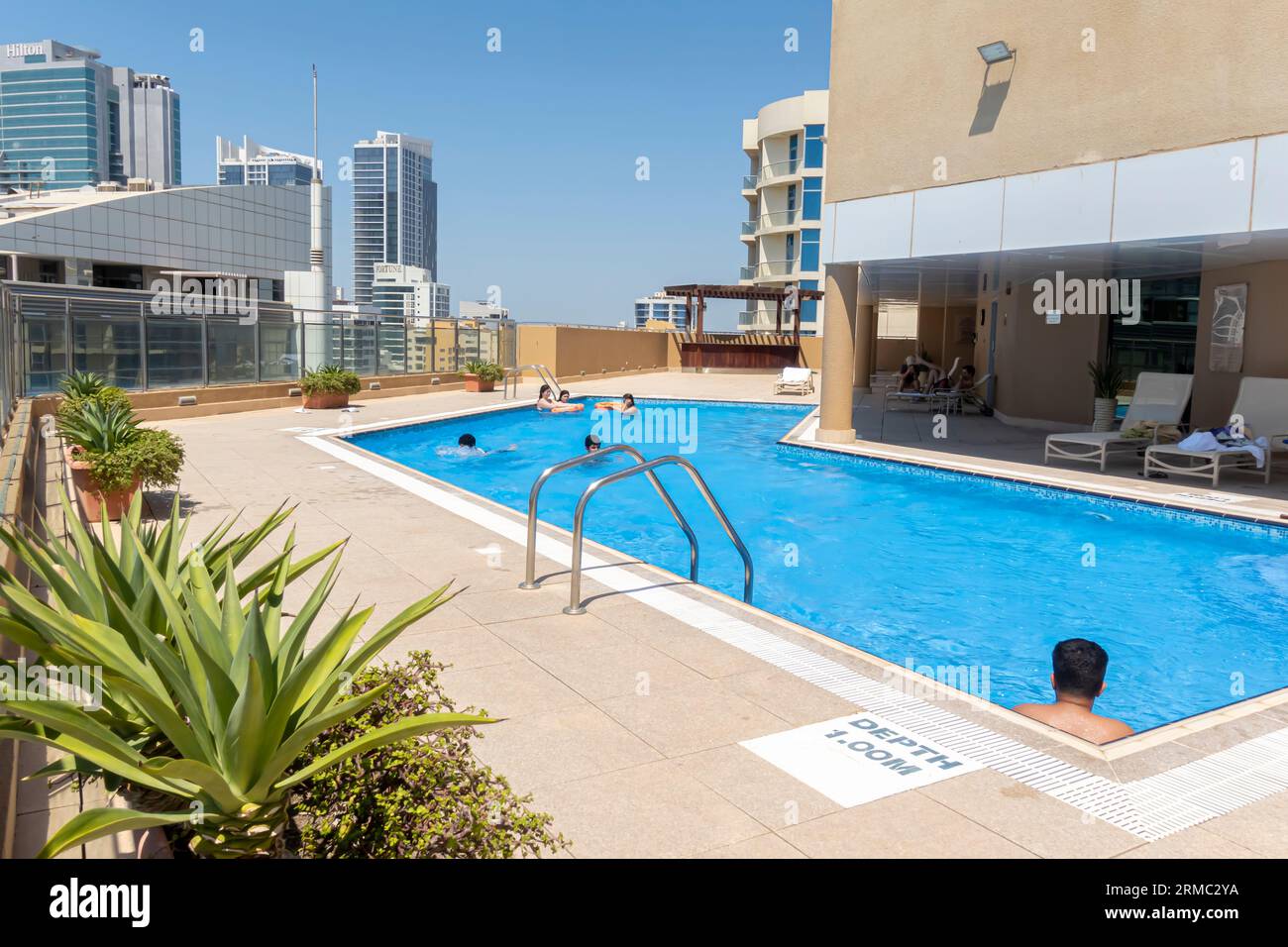 Piscine sur le toit, les gens nagent dans une petite piscine sur le toit avec vue sur la ville. Affiche de profondeur de 1 mètres sur le sol Banque D'Images