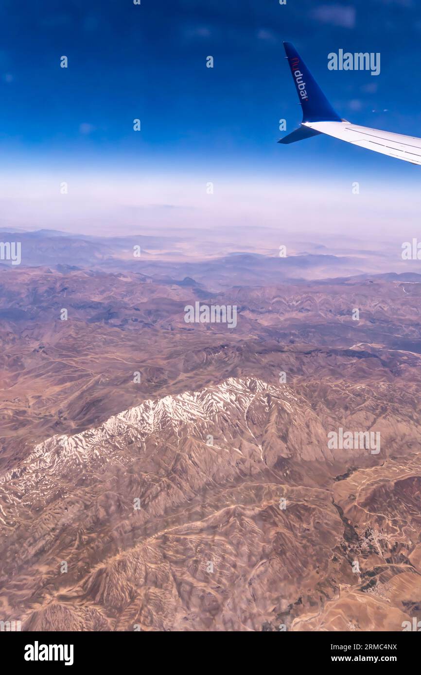 Montagnes avec neige, ciel bleu - vue par la fenêtre de l'avion, aile d'avion flydubai compagnie aérienne - vue aérienne depuis un siège de fenêtre d'avion Banque D'Images