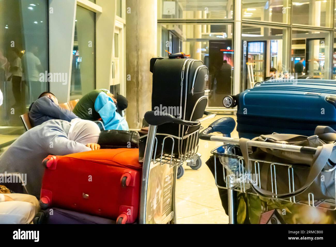 Les touristes dorment dans le terminal de l'aéroport sur les bagages à Amman Airport Jordan Banque D'Images