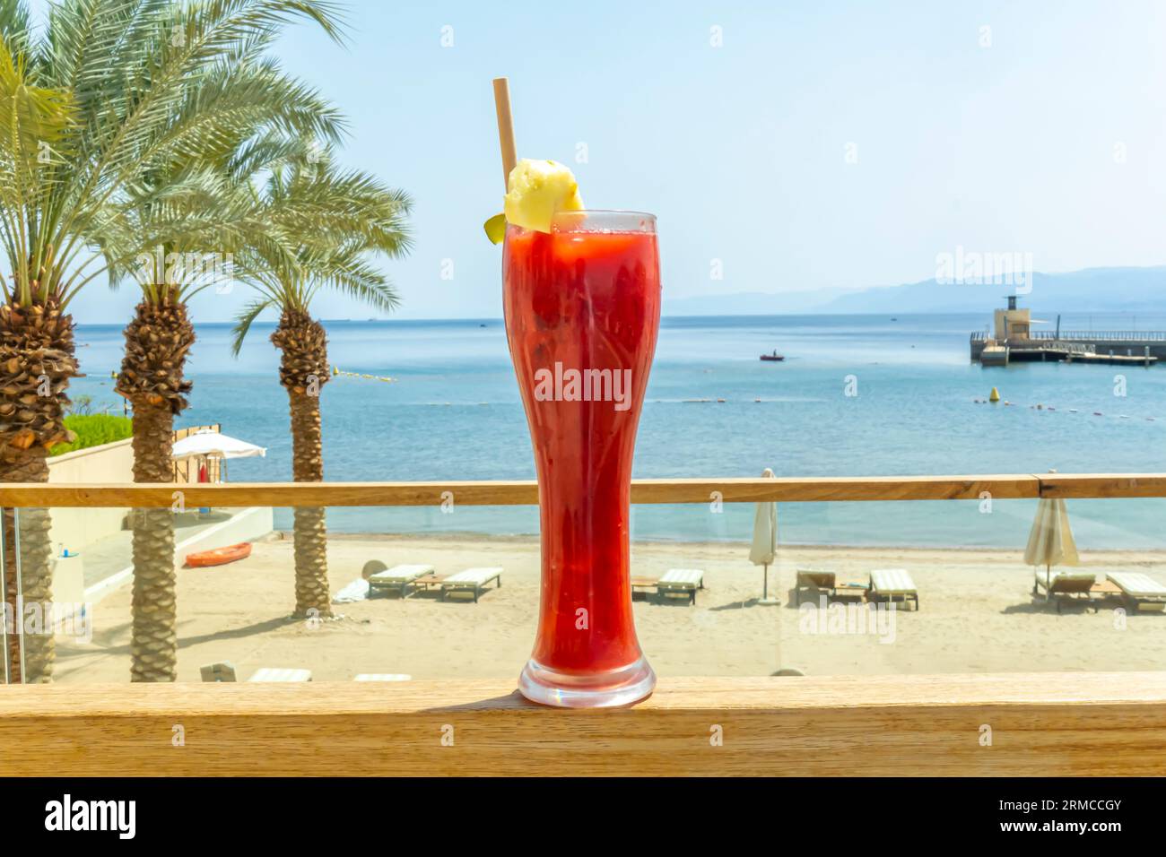 Verre de cocktail smoothie au jus de fraise au citron contre un paysage tropical, mer d'Arabie. Concept de boissons des stations de plages tropicales Banque D'Images