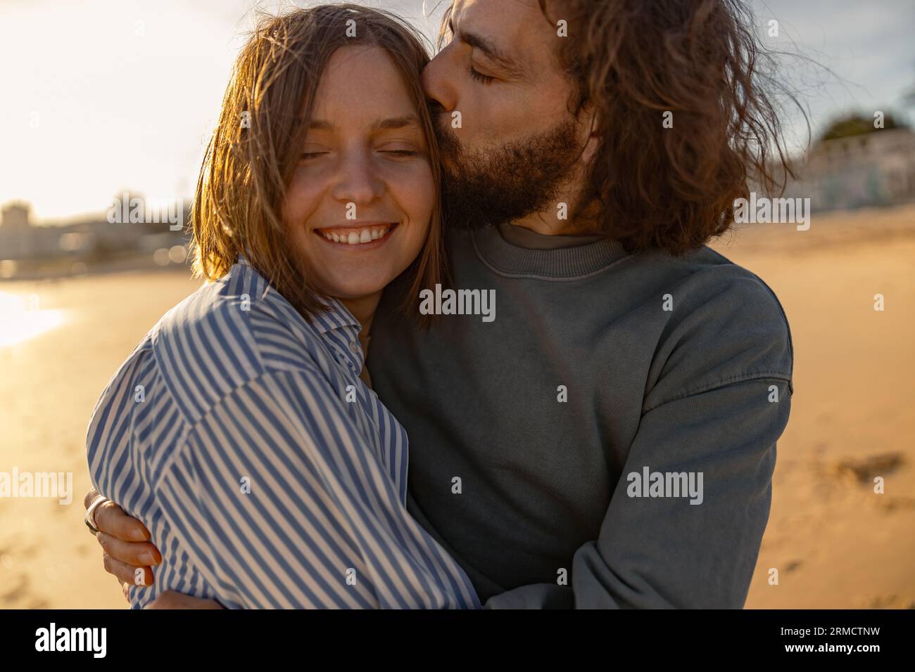 Gros plan de couple amoureux embrassant et embrassant tout en marchant le long de la plage par jour ensoleillé venteux Banque D'Images