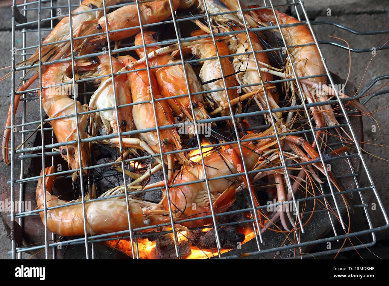 Beaucoup de crevettes géantes d'eau douce sont grillées dans le gril sur le feu de charbon de bois. Sa couleur est orange, semble appétissant. Banque D'Images