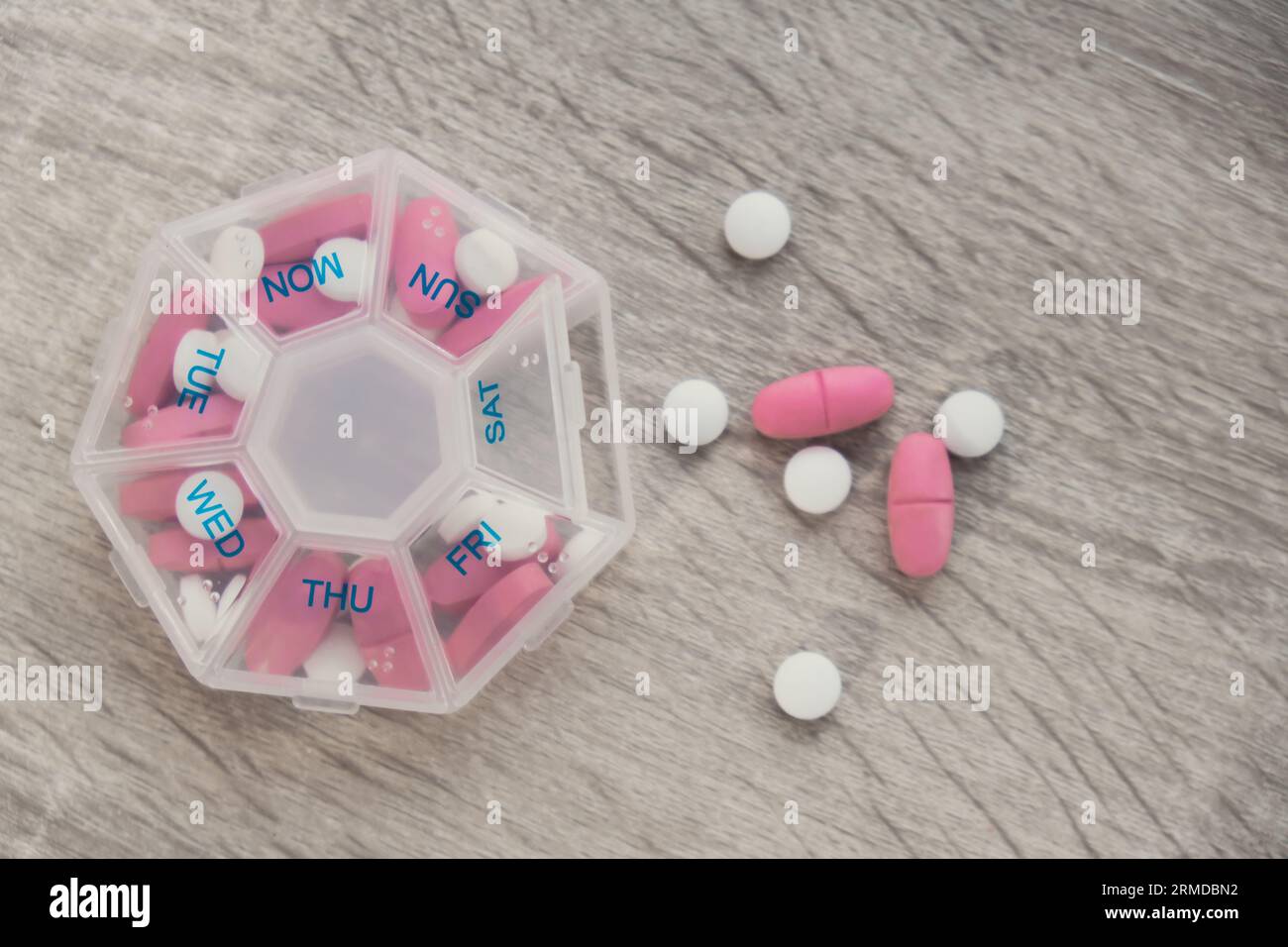 Organiseur injections hebdomadaires gros plan de la boîte de pilules médicales avec des doses de comprimés pour la journée prendre des médicaments avec des médicaments blancs roses et des capsules. Vitamines quotidiennes à la maison. Médicaments compléments alimentaires, immunité et prévention des maladies huile de poisson gel Softgel, vitamine D et C minéraux oméga, fibres, acides aminés gras, probiotiques sédatifs. Les soins de santé et les maladies guérissent Banque D'Images