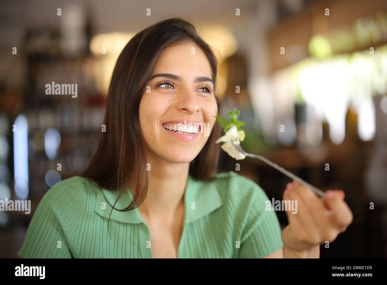 Femme heureuse mangeant de la laitue au déjeuner souriant dans un restaurant Banque D'Images