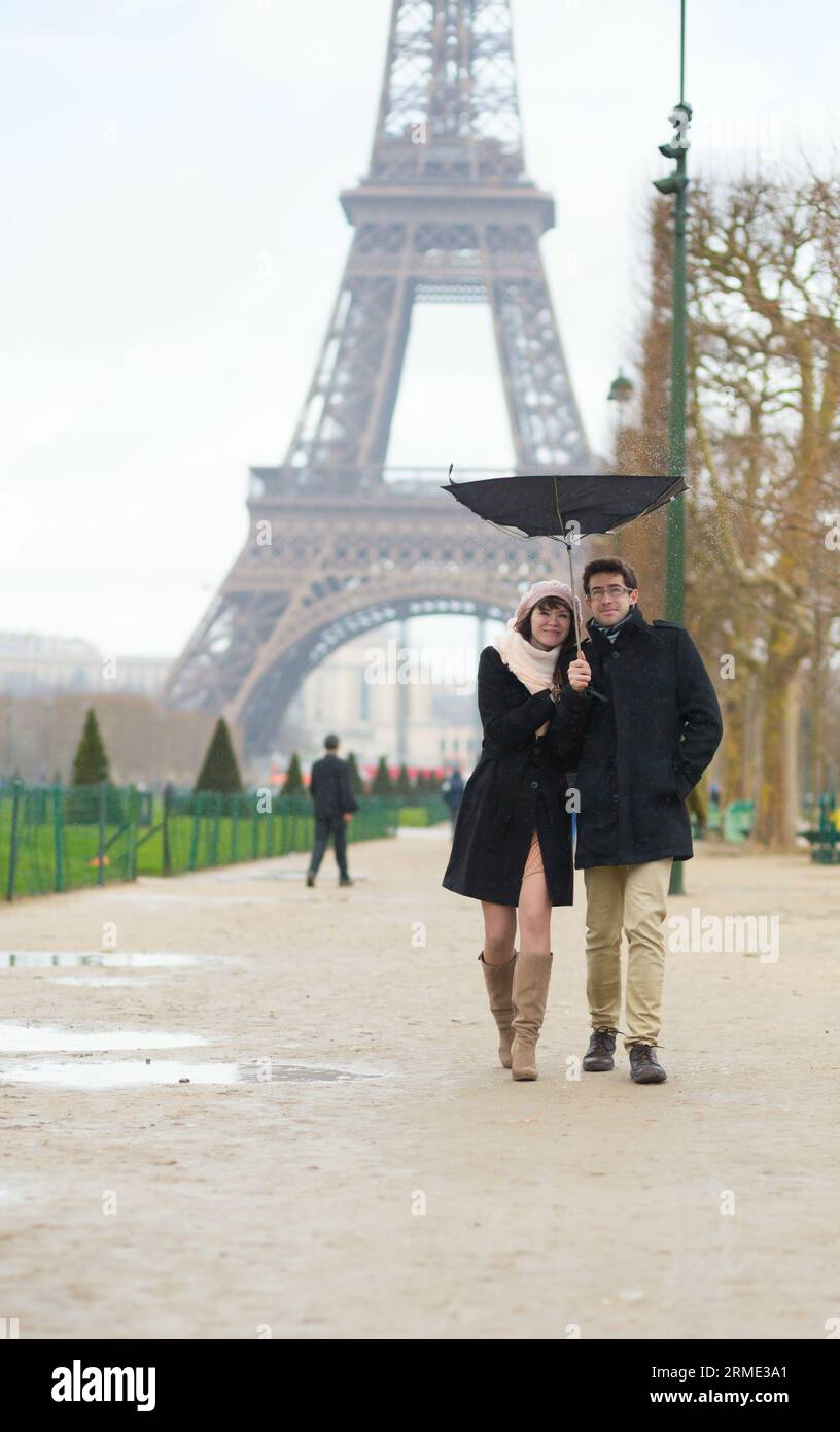Couple marchant sous la pluie avec un parapluie cassé Banque D'Images