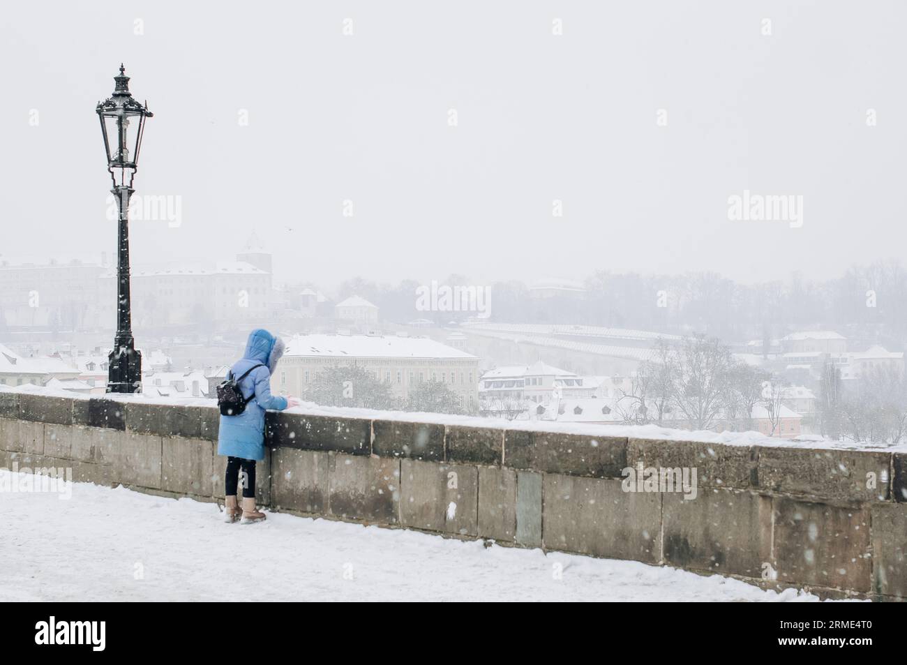 Une fille portant un manteau bleu et une capuche regarde vers le bas depuis le pont. Banque D'Images