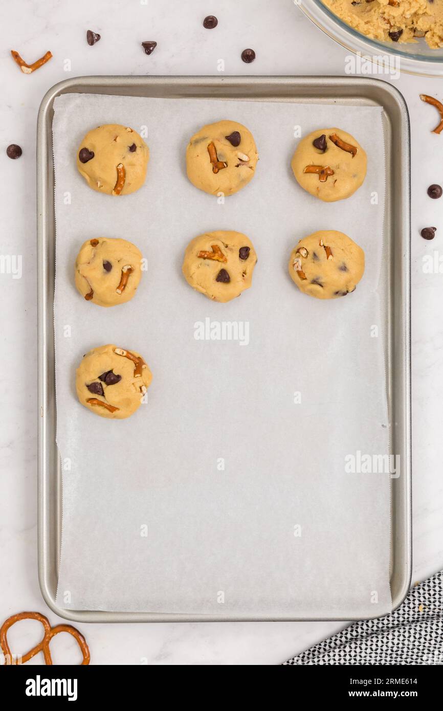 Biscuits crus au bretzel aux pépites de chocolat sur une plaque de cuisson avec du papier parchemin Banque D'Images