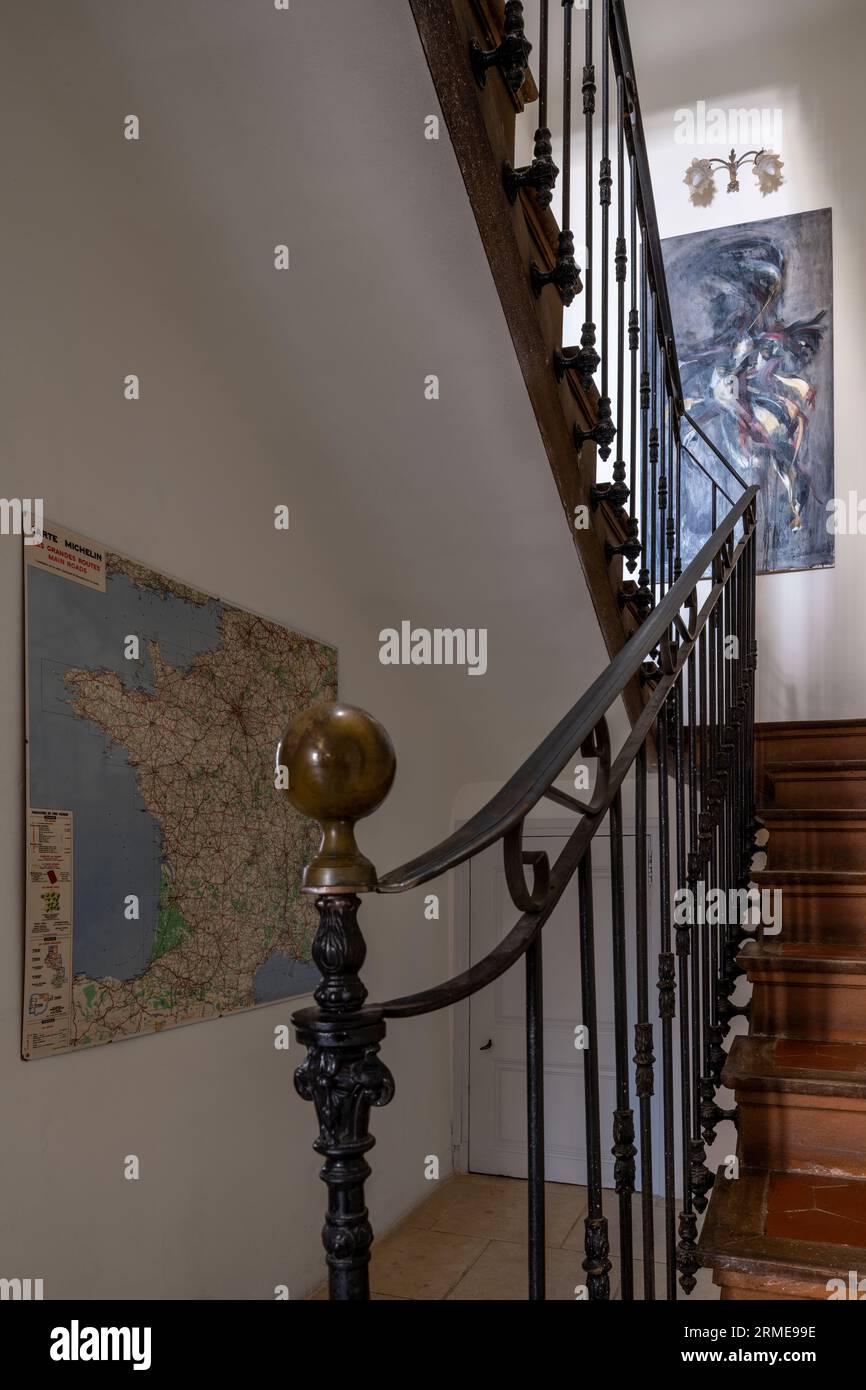 Ancienne rampe en métal sur escalier avec carte et œuvres d'art dans le couloir Cotignac, Var, France. Banque D'Images