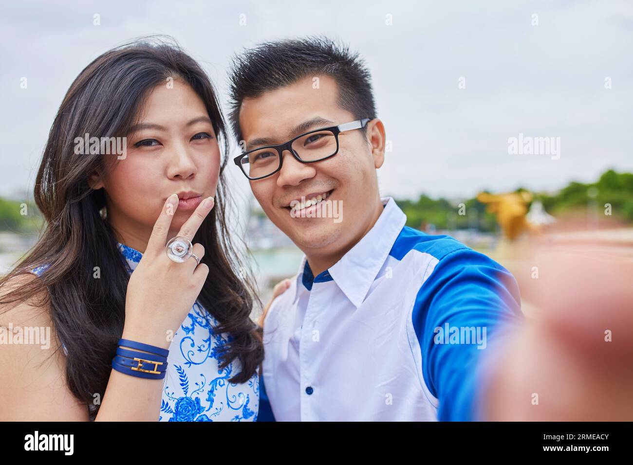 Beau couple asiatique de touristes passant leurs vacances à Paris et prenant selfie avec un téléphone portable, fille montre un signe V, un geste populaire Banque D'Images
