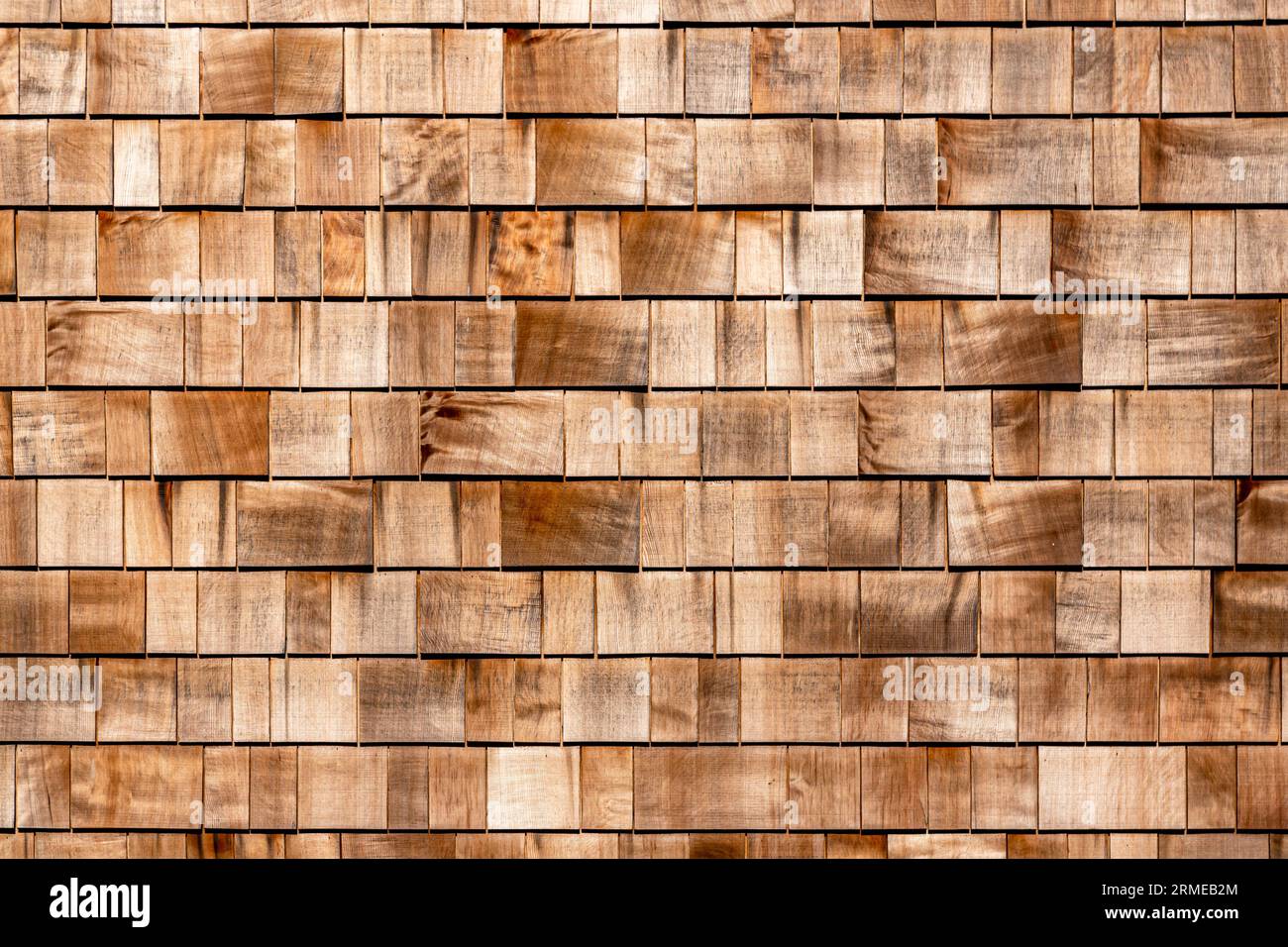 Panneau de toit en rangée de parement en bois de cèdre rouge shake en bardeau fait de conifère de mélèze. Fond de bardeaux en bois. Texture de fond de bardeaux de bois brun. Carrelage en bois couvert de mur de maison comme arrière-plan Banque D'Images