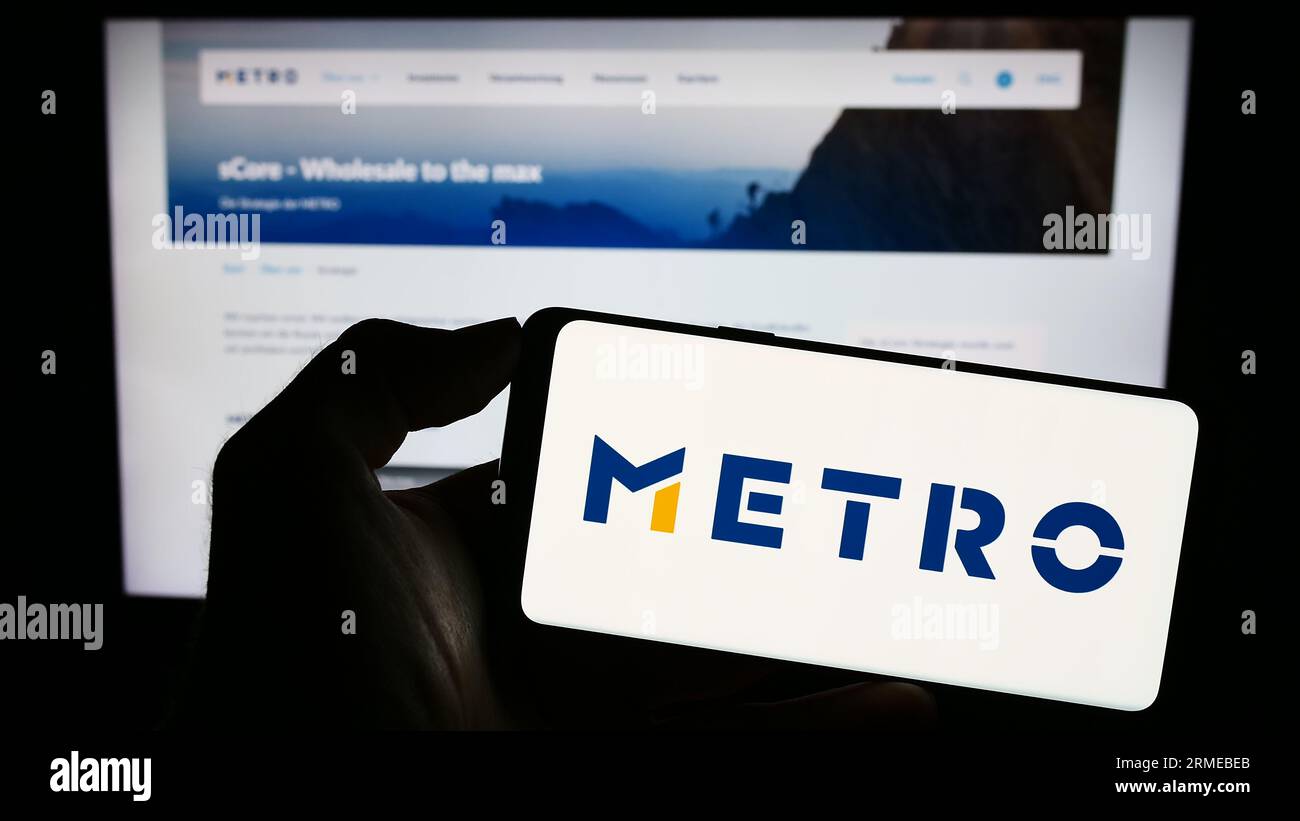 Personne tenant le smartphone avec le logo de la société allemande de gros Metro AG sur l'écran en face du site Web. Concentrez-vous sur l'affichage du téléphone. Banque D'Images