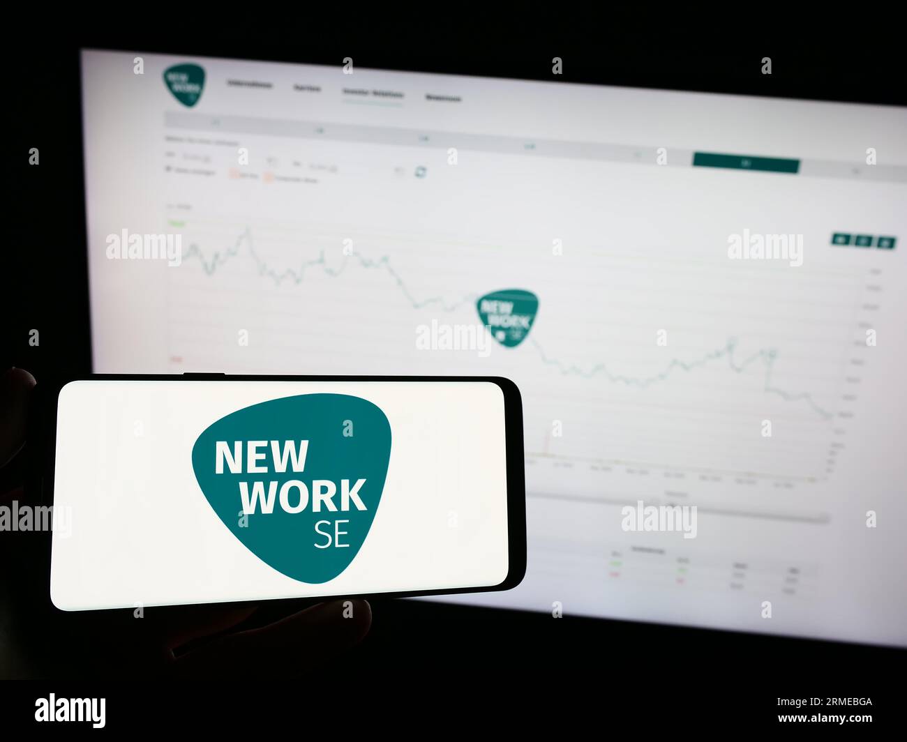 Personne tenant le téléphone mobile avec le logo de la société allemande New Work se (XING) sur l'écran en face de la page Web de l'entreprise. Concentrez-vous sur l'affichage du téléphone. Banque D'Images