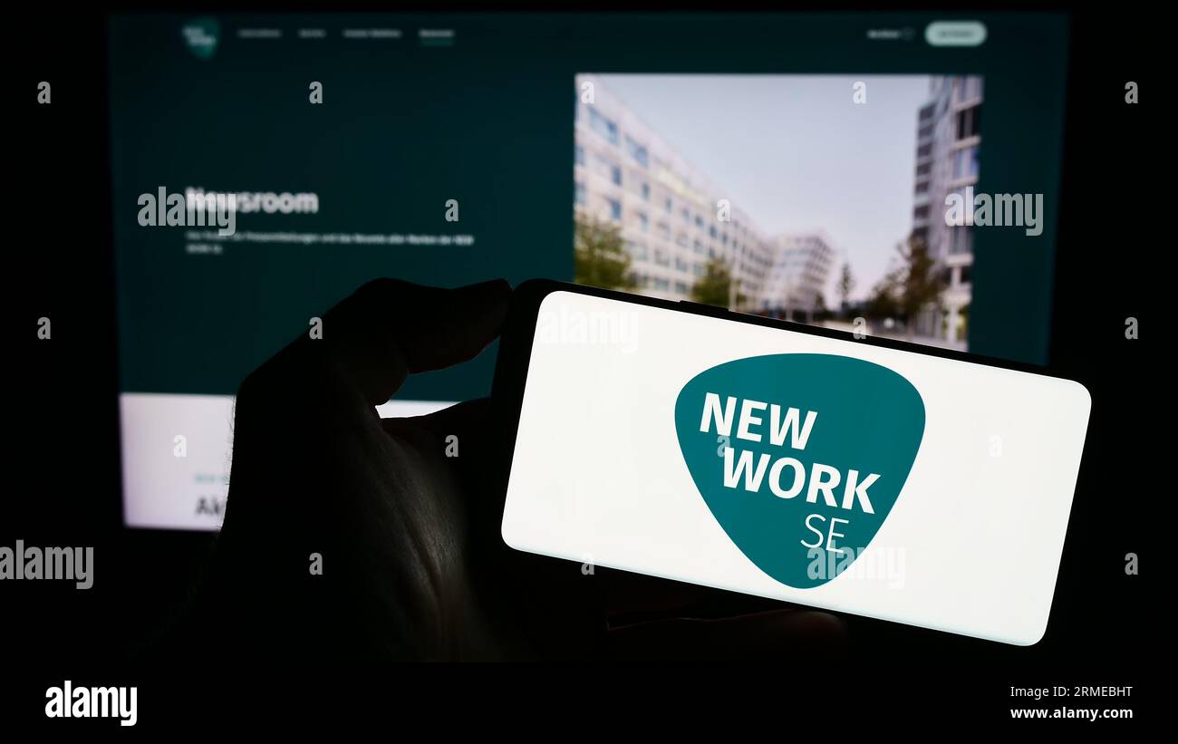 Personne tenant le téléphone portable avec le logo de la société allemande New Work se (XING) sur l'écran en face de la page Web de l'entreprise. Concentrez-vous sur l'affichage du téléphone. Banque D'Images