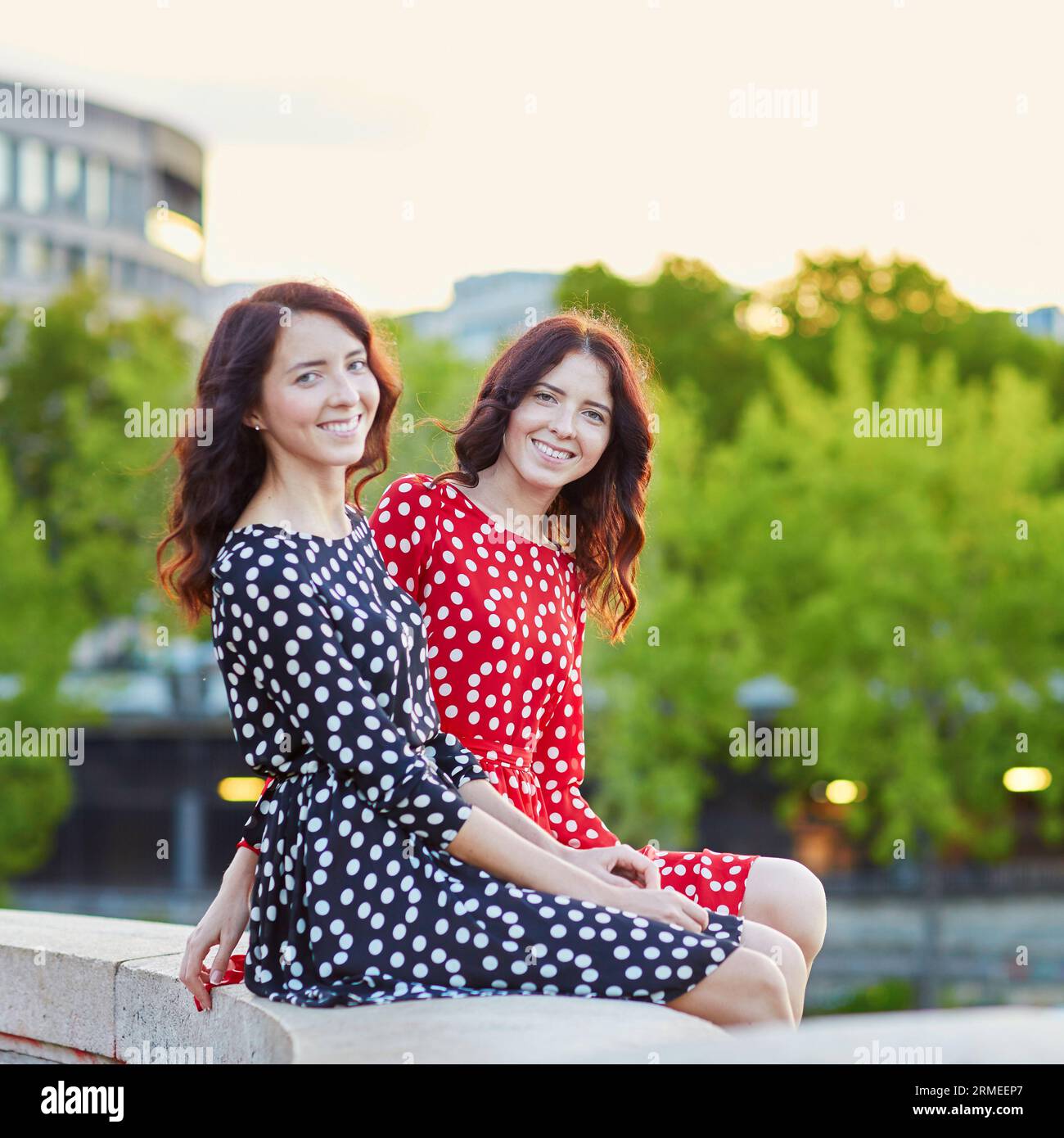 Belles sœurs jumelles en rouge et noir robes à pois à l'extérieur un jour d'été Banque D'Images