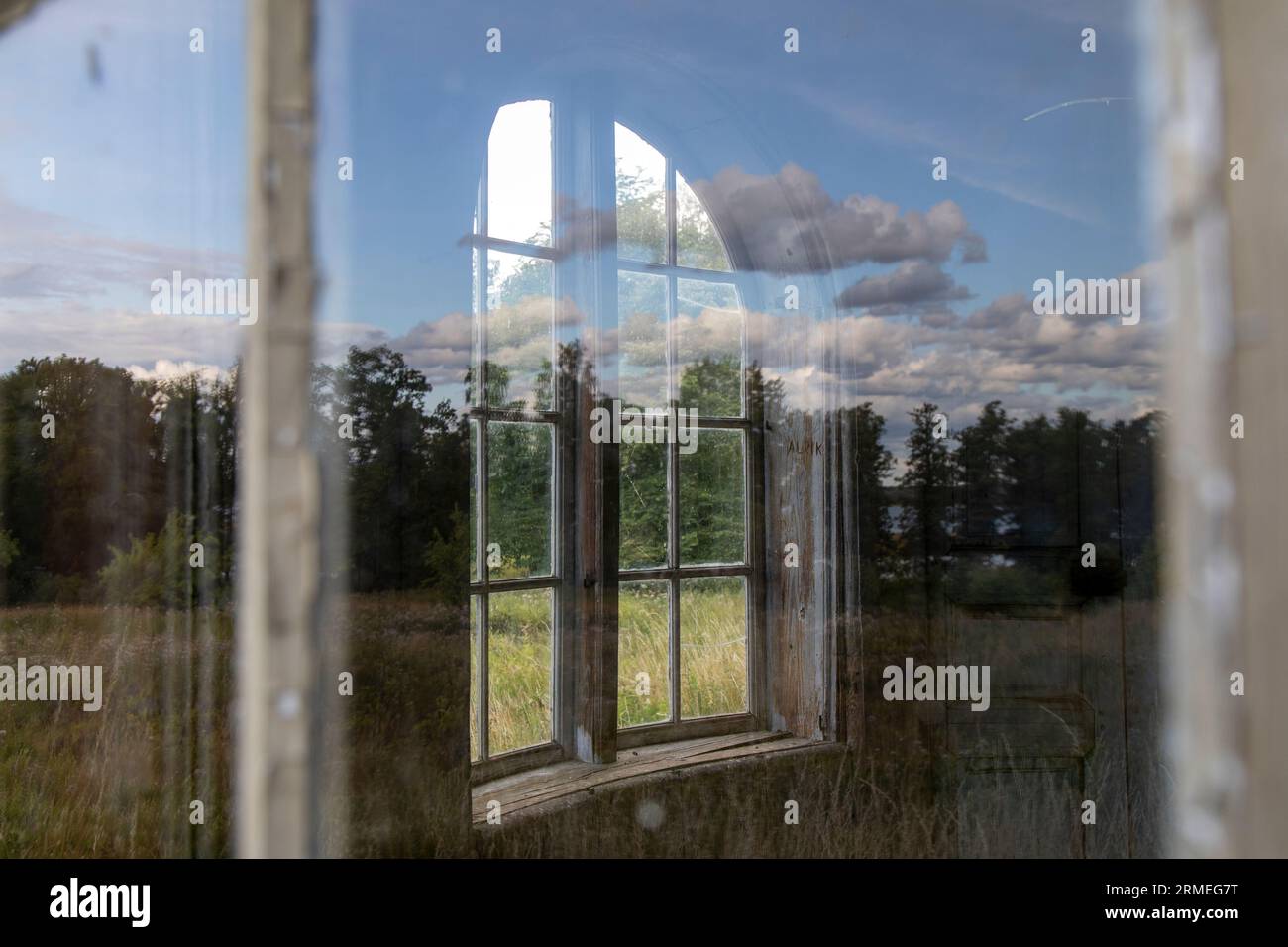Une vue de l'intérieur d'une fenêtre dans une ferme abandonnée, montrant un paysage rustique et rural Banque D'Images