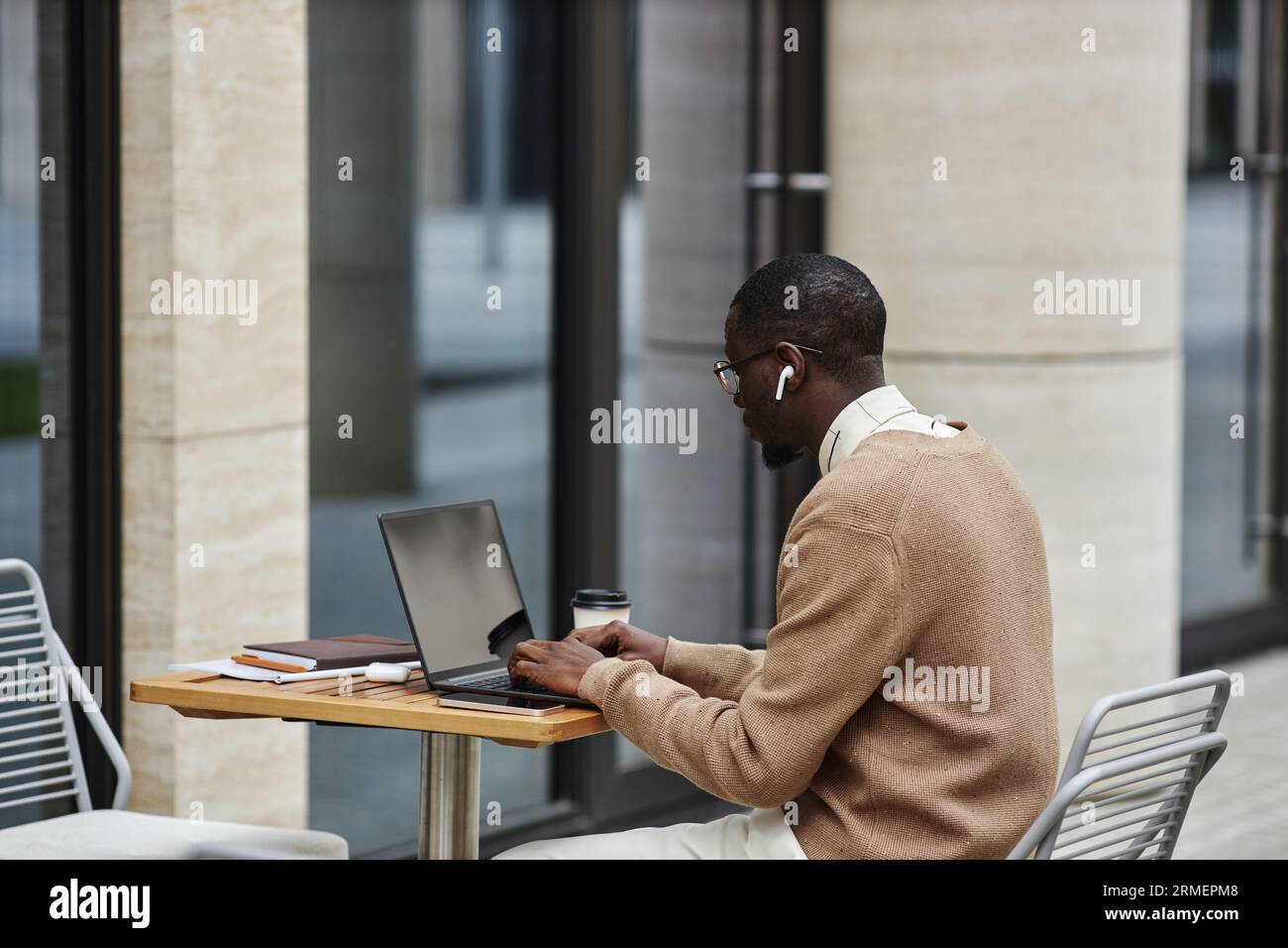Jeune homme afro-américain cols blancs regardant l'écran d'ordinateur portable et tapant sur le clavier tout en travaillant sur un nouveau projet d'entreprise Banque D'Images
