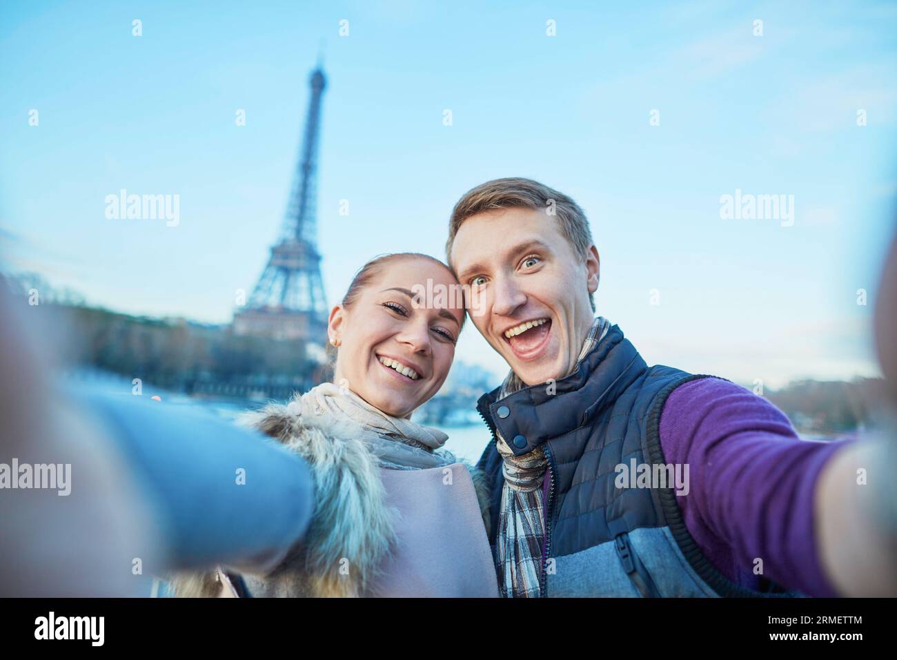 Heureux couple souriant prenant selfie avec leur téléphone portable avec la tour Eiffel à Paris, France Banque D'Images