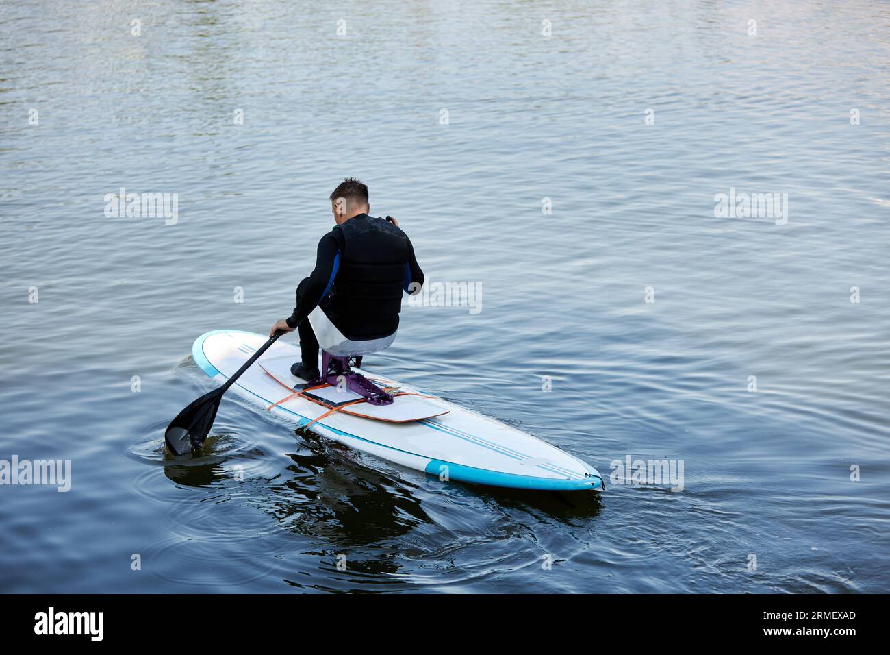 Portrait minimal de l'homme adulte avec handicap équitation sup board appréciant les sports nautiques à l'extérieur dans la nature, espace de copie Banque D'Images