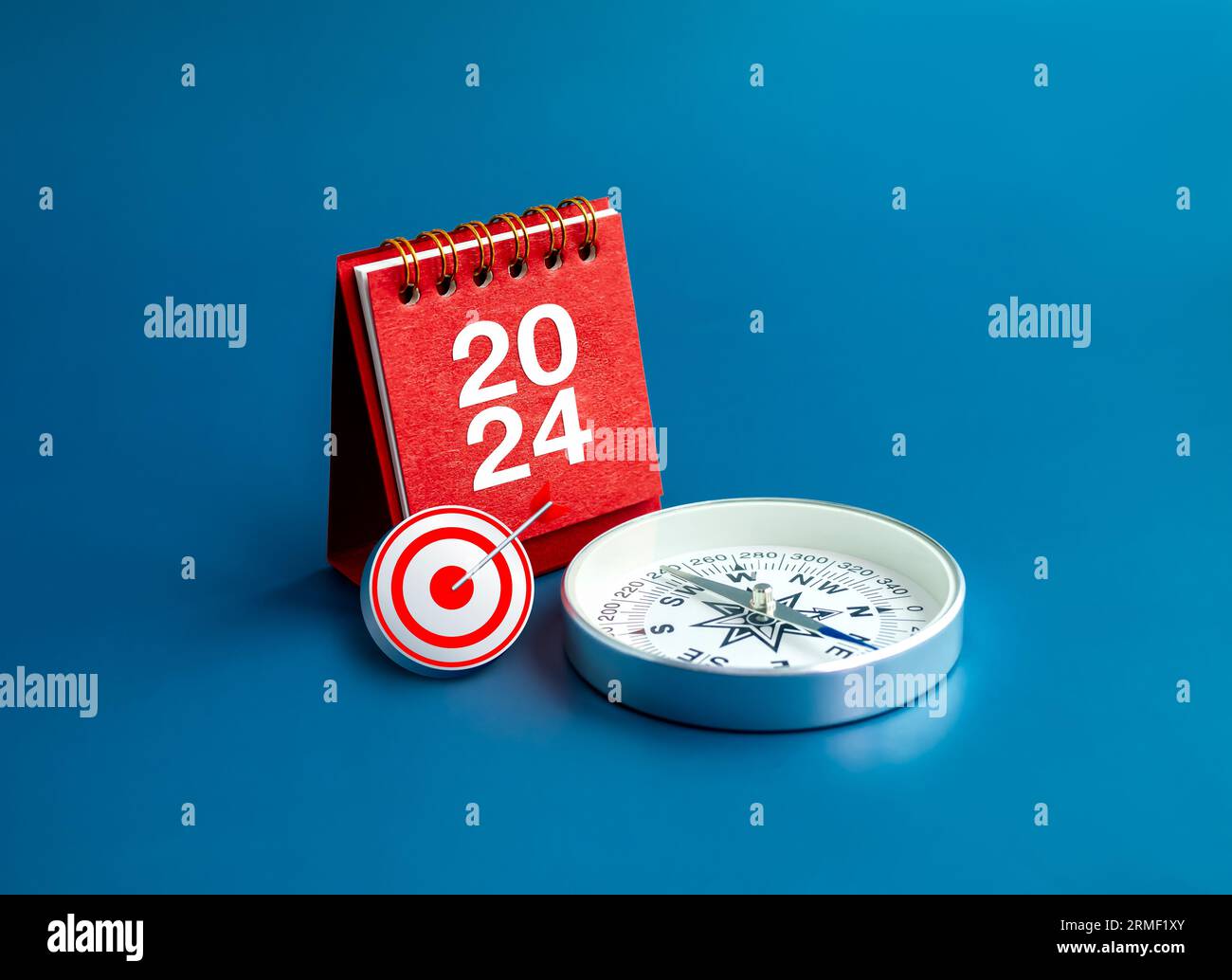 Bonne année 2024 fond de bannière. Icône cible 3d, 2024 chiffres année sur le support de couverture de calendrier de bureau rouge et boussole sur fond bleu, styl minimal Banque D'Images