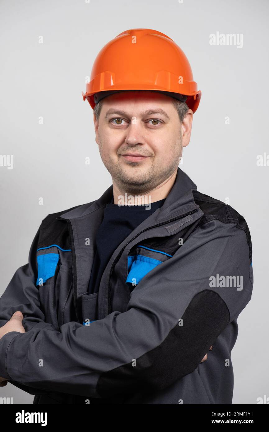 Un jeune homme ouvrier de construction dans un casque de sécurité et uniforme de travail sur un fond blanc Banque D'Images