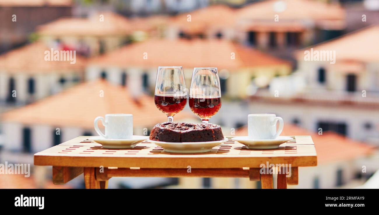 Deux verres de vin de Madère, deux tasses de café expresso frais et dessert traditionnel portugais au miel et aux noix Bolo de mel dans un café avec vue sur Funch Banque D'Images