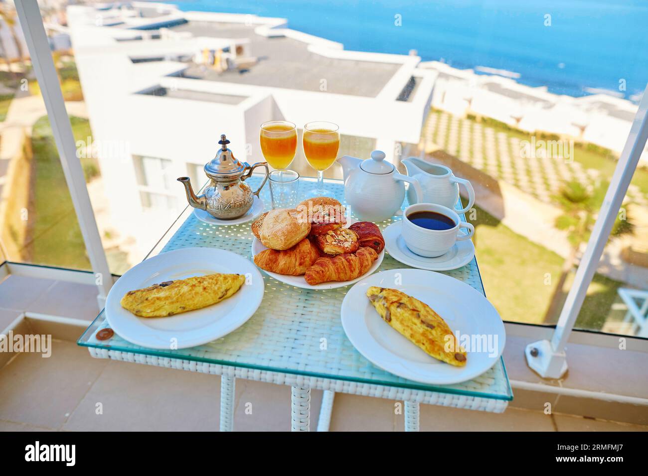 Délicieux petit déjeuner avec omelette, pâtisserie, café et thé à la menthe servi sur le balcon avec vue sur la mer dans l'hôtel marocain Banque D'Images