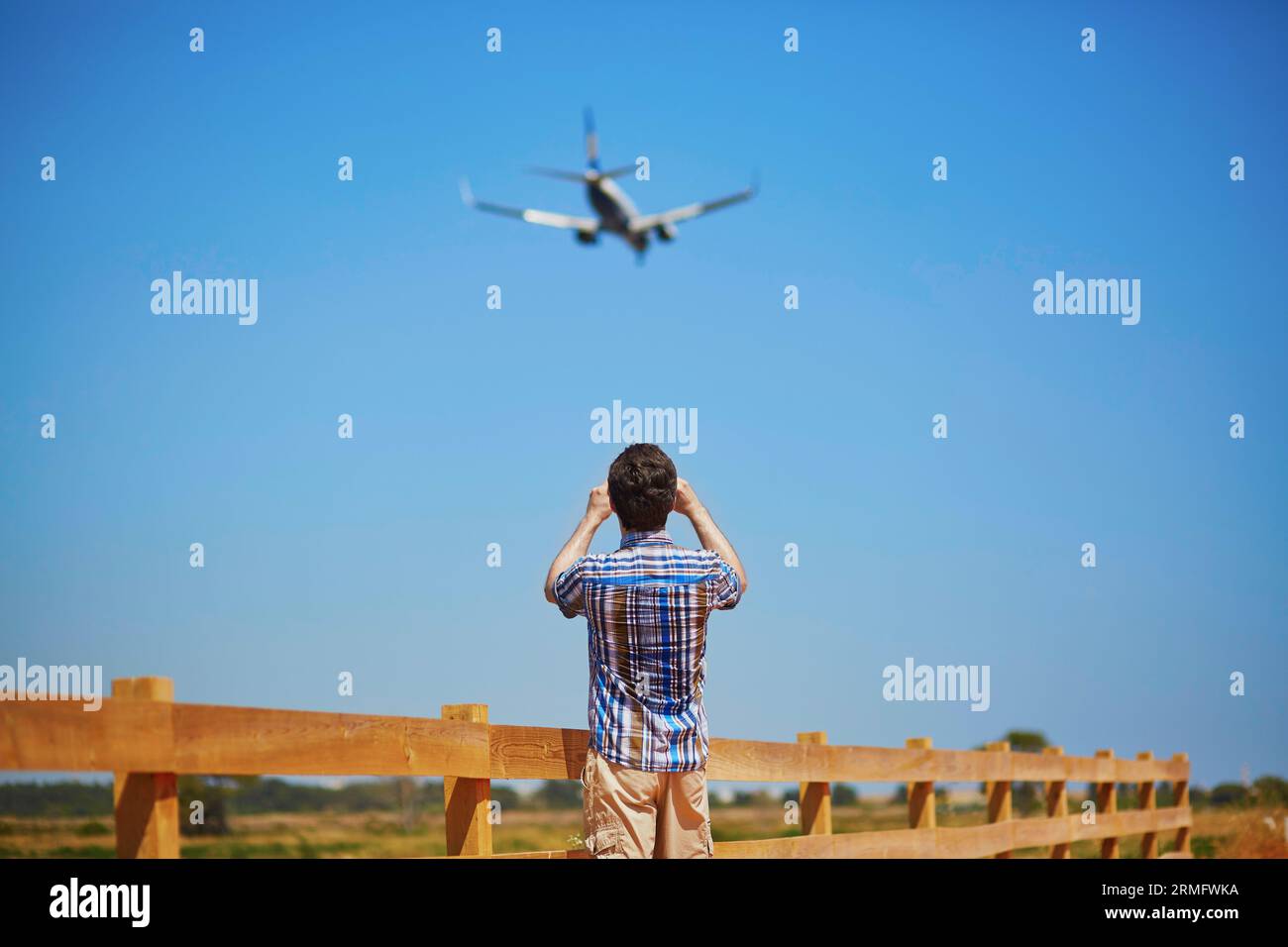 L'homme regarde la trajectoire de descente et l'avion d'atterrissage ou en prend une photo. Concept de repérage d'avion Banque D'Images