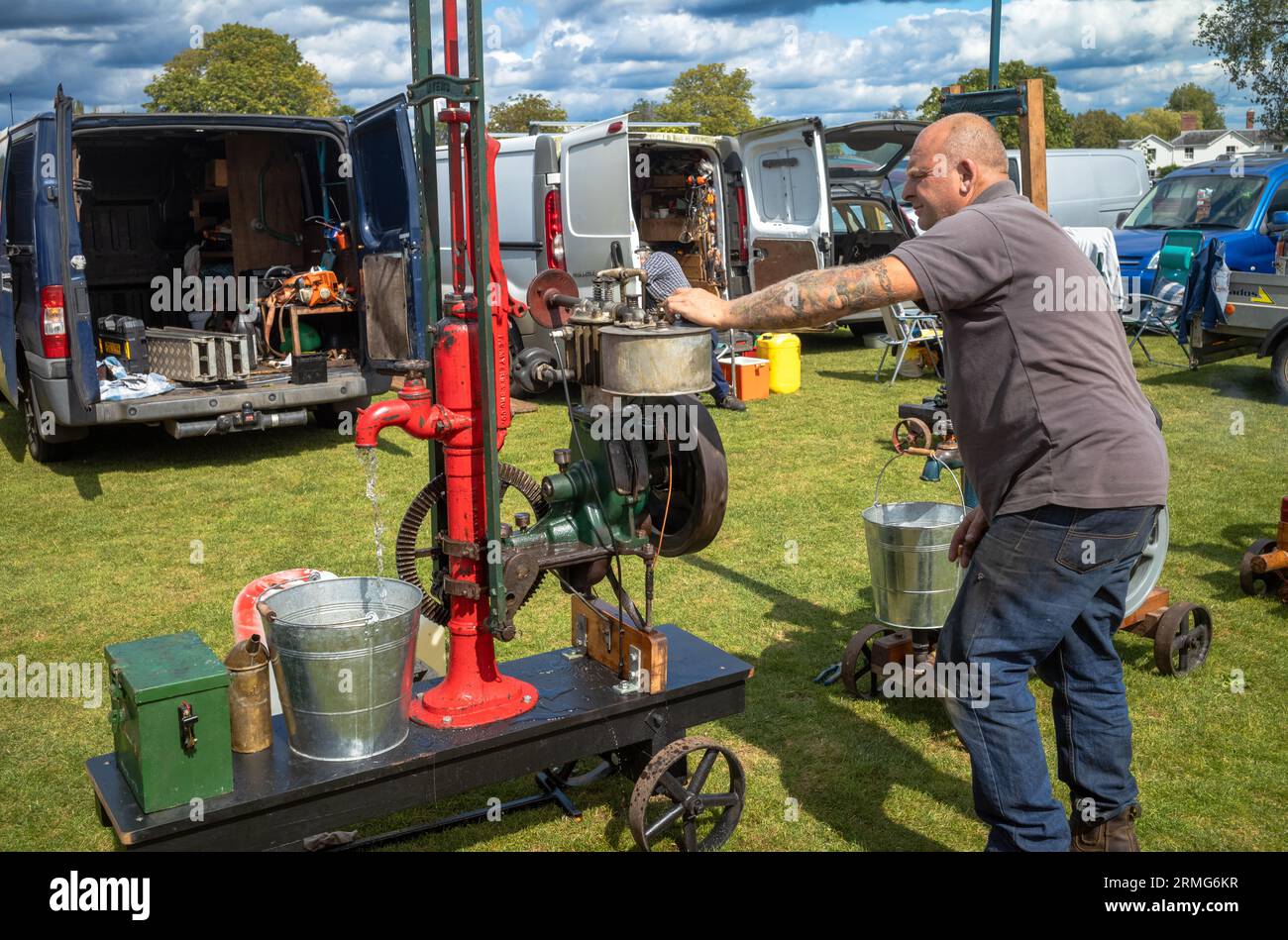 Un passionné de moteurs stationnaires vintage homme ajuste sa machine lors d'une fête de village à Wisborough Green, West Sussex, Royaume-Uni. Banque D'Images