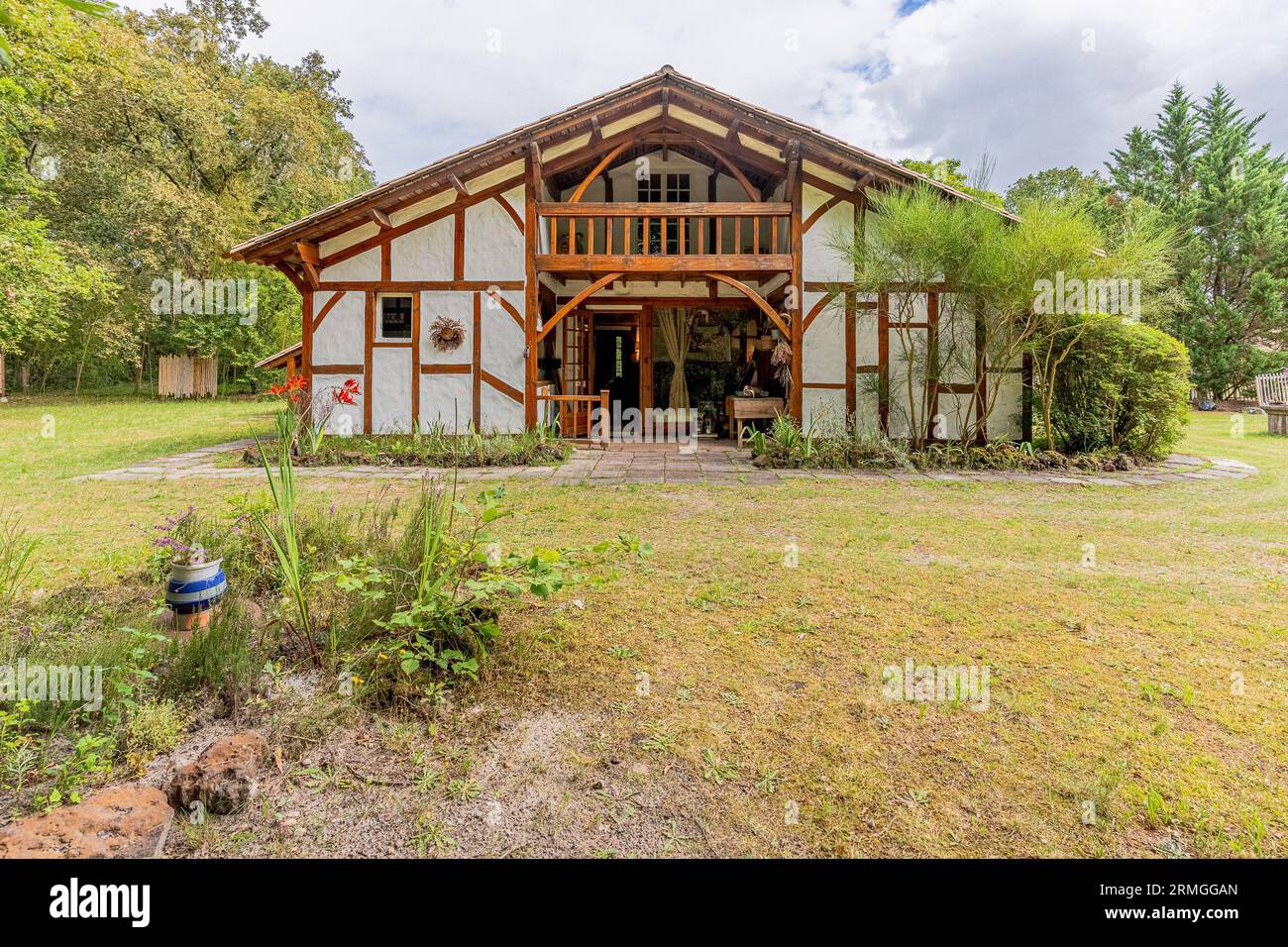 Une maison de deux étages avec un porche enveloppant situé dans un paysage luxuriant et herbeux, entouré de grands arbres Banque D'Images