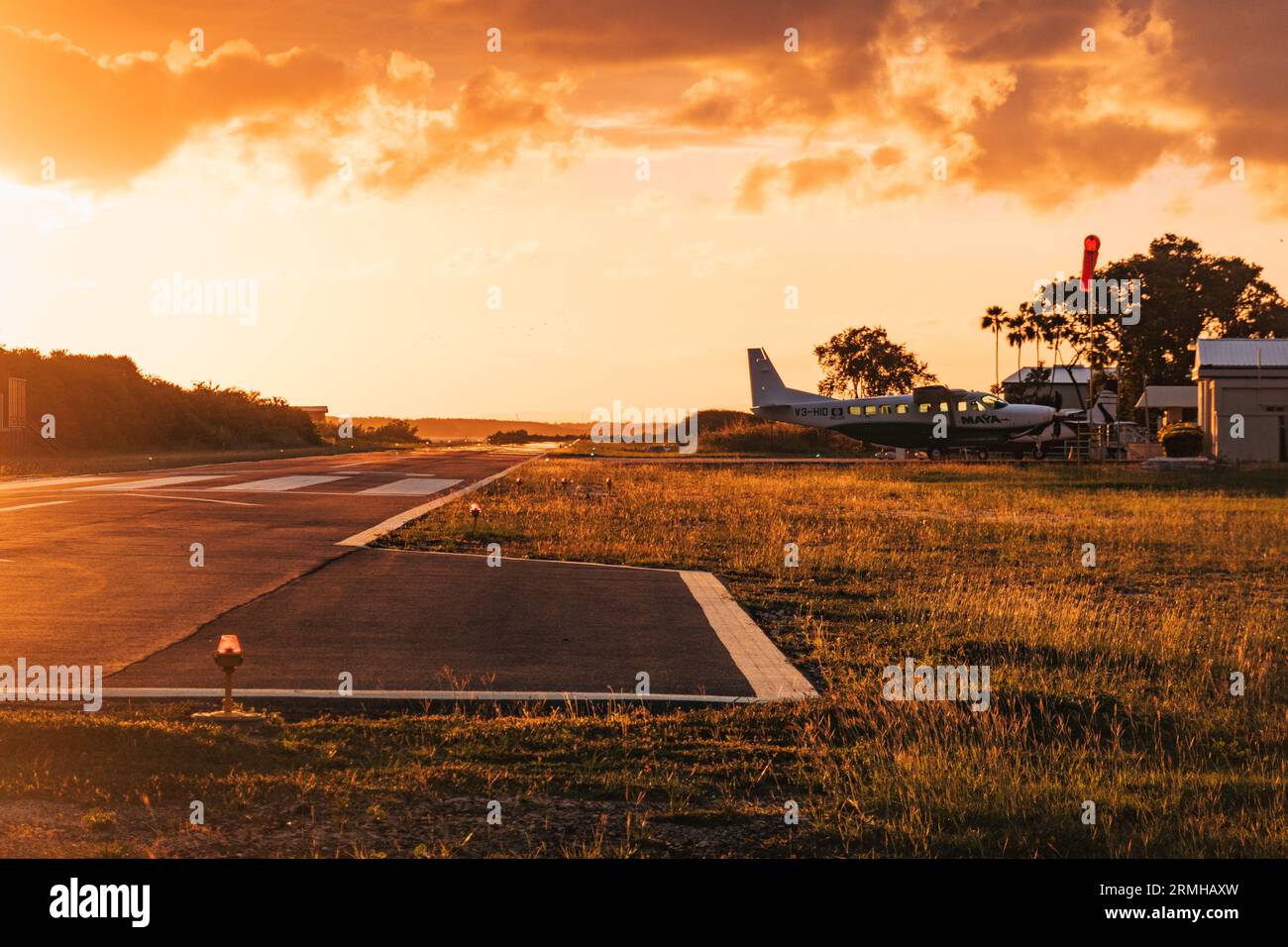 Les couleurs or et orange du coucher du soleil frappent la piste de l'aéroport de Placencia, au sud-est du Belize Banque D'Images