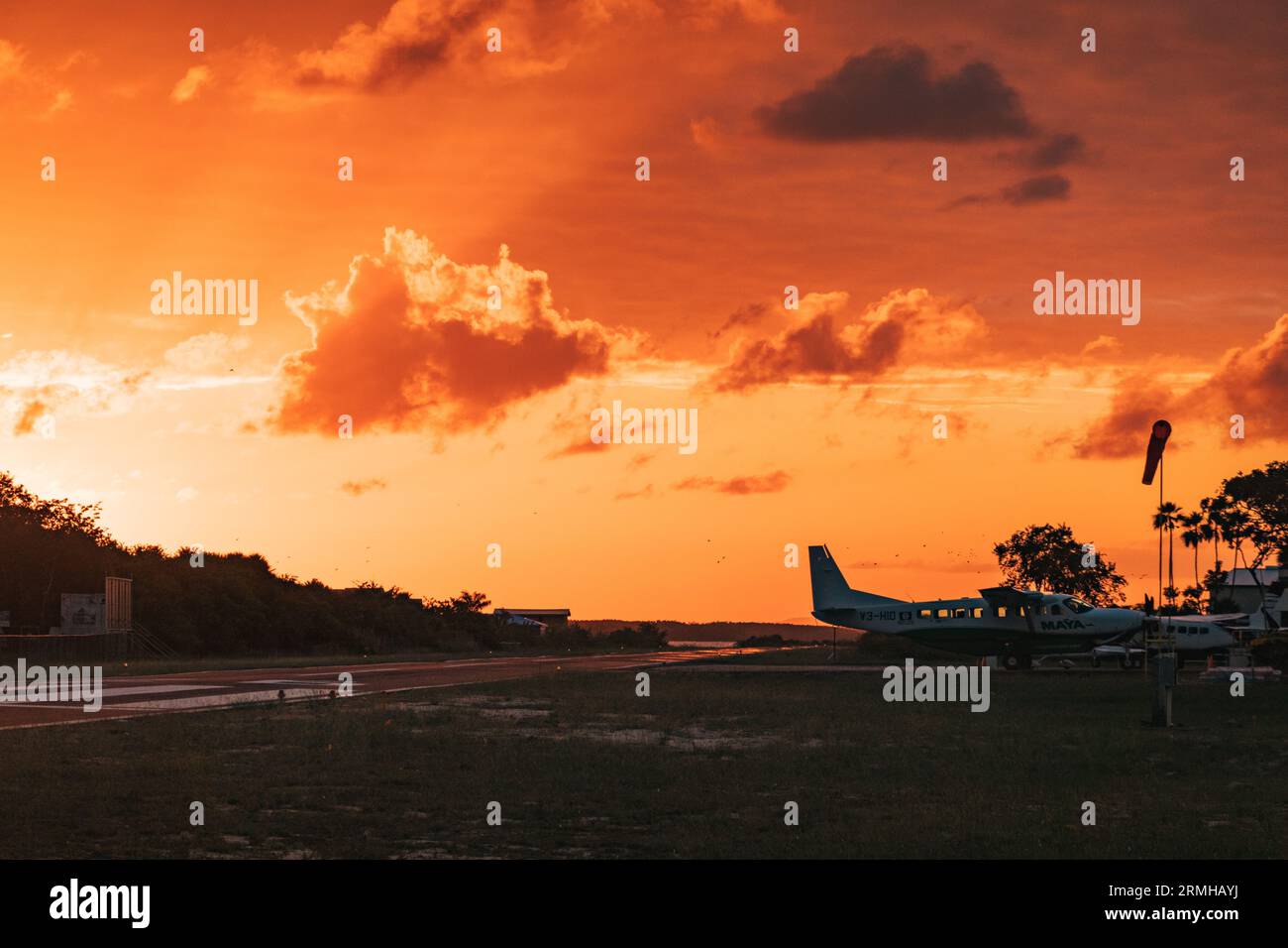 Les couleurs or et orange du coucher du soleil frappent la piste de l'aéroport de Placencia, au sud-est du Belize Banque D'Images