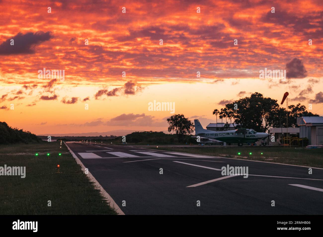 Les couleurs or et orange du coucher du soleil frappent la piste de l'aéroport de Placencia, au sud-est du Belize Banque D'Images