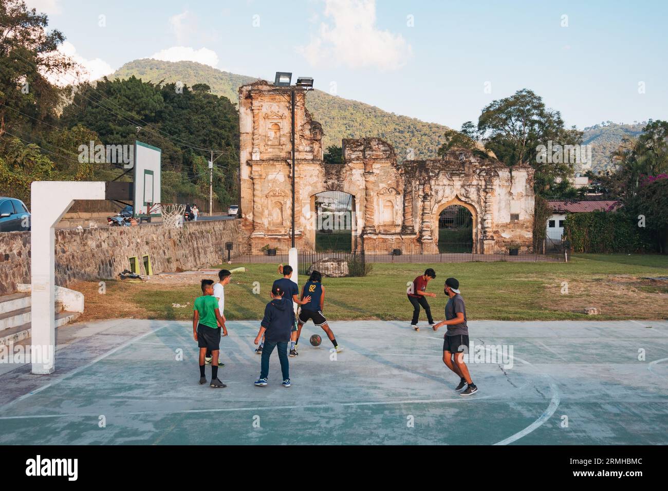 Les enfants jouent au basket-ball sur un court public, avec les ruines d'un bâtiment colonial espagnol reposant derrière, à Antigua Guatemala Banque D'Images