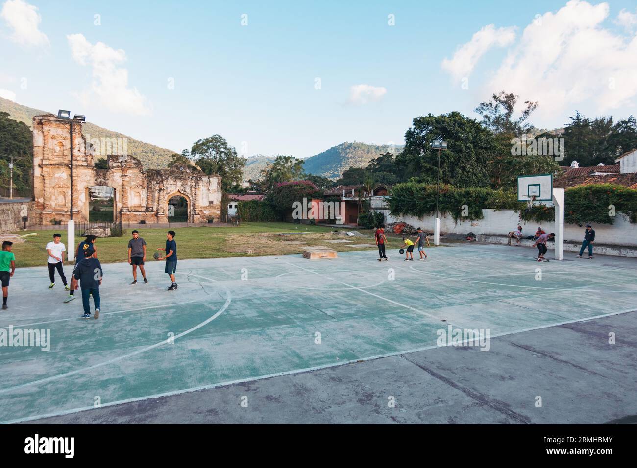 Les enfants jouent au basket-ball sur un court public, avec les ruines d'un bâtiment colonial espagnol reposant derrière, à Antigua Guatemala Banque D'Images