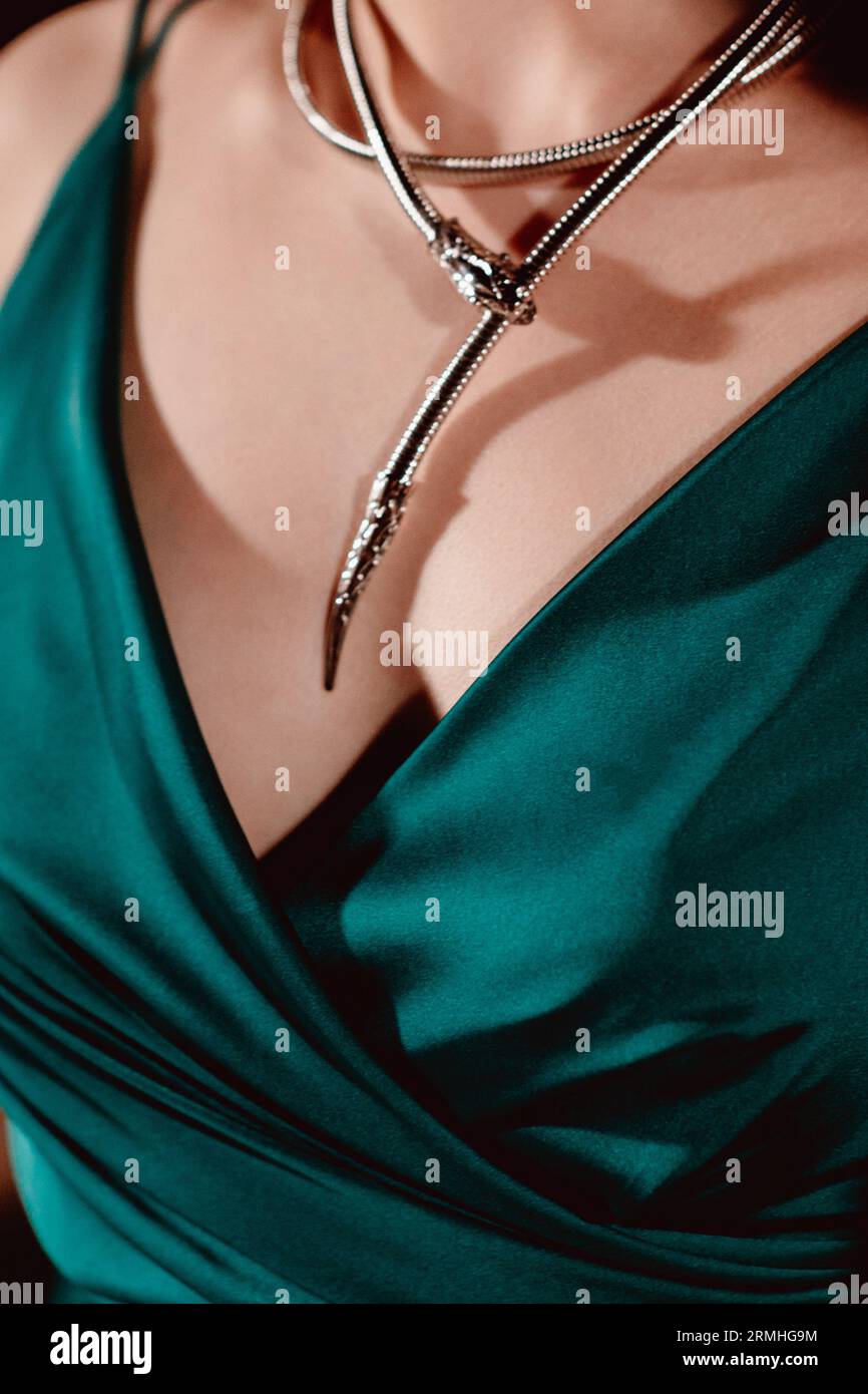 Corps féminin dans une robe verte élégante soyeuse avec des bijoux de cou argenté. Concept de vêtements élégants et accessoires fantaisie Banque D'Images