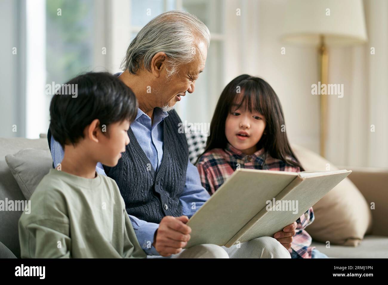 grand-père asiatique ayant un bon moment à raconter l'histoire à mignon petit-fils et petite-fille Banque D'Images
