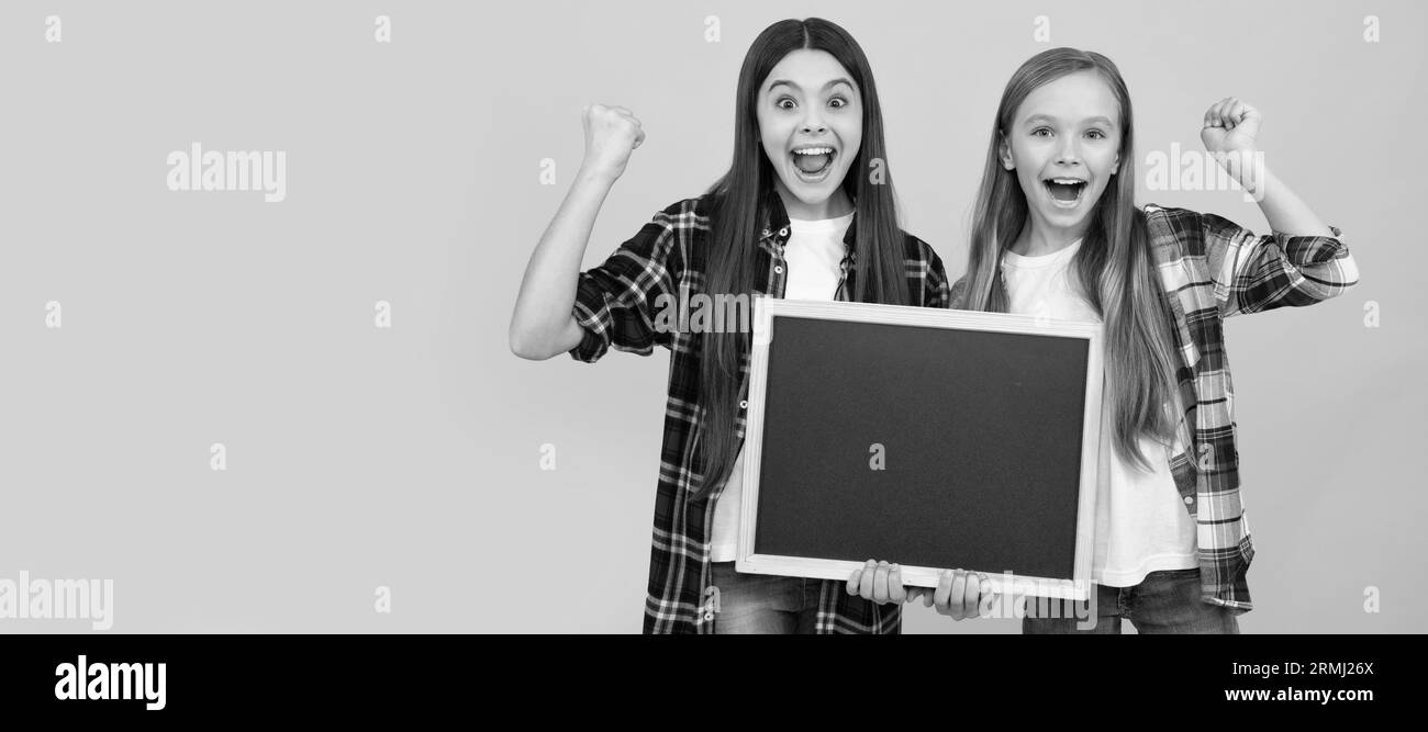 Les filles de l'école amis. Les enfants heureux dans le casual checked tiennent le tableau noir de l'école pour l'espace de copie, le succès. Bannière de l'élève de la jeune fille. Enfant de l'école Banque D'Images