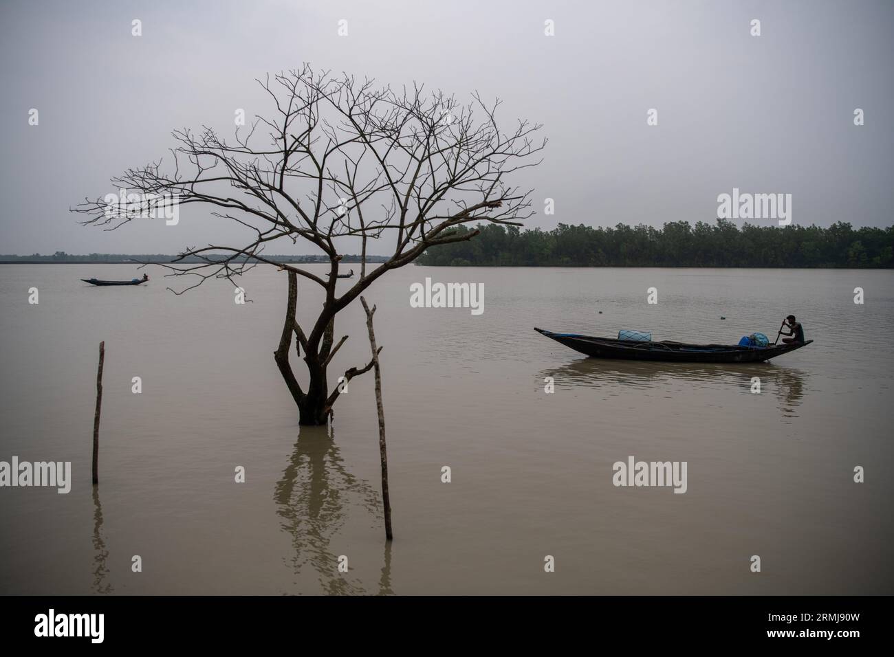 Un pêcheur vu rentrer chez lui après avoir pêché dans une zone côtière à Kalabogi dans Khulna. Il n'y a pas si longtemps, Kalabogi, un village côtier du Bangladesh, était plein de terres cultivables jusqu'à ce que la montée du niveau de la mer commence à envahir la région jusqu'au golfe du Bengale. De fréquents cyclones et inondations frappent le village depuis la fin des années 1990 En 2009, un cyclone majeur nommé Aila a détruit les 1 400 kilomètres de remblais du pays, 8 800 kilomètres de routes et environ 3 50 000 acres de terres agricoles. Plusieurs centaines de personnes auraient été tuées dans la catastrophe. Les fermiers de Kalabogi étaient les pires h Banque D'Images